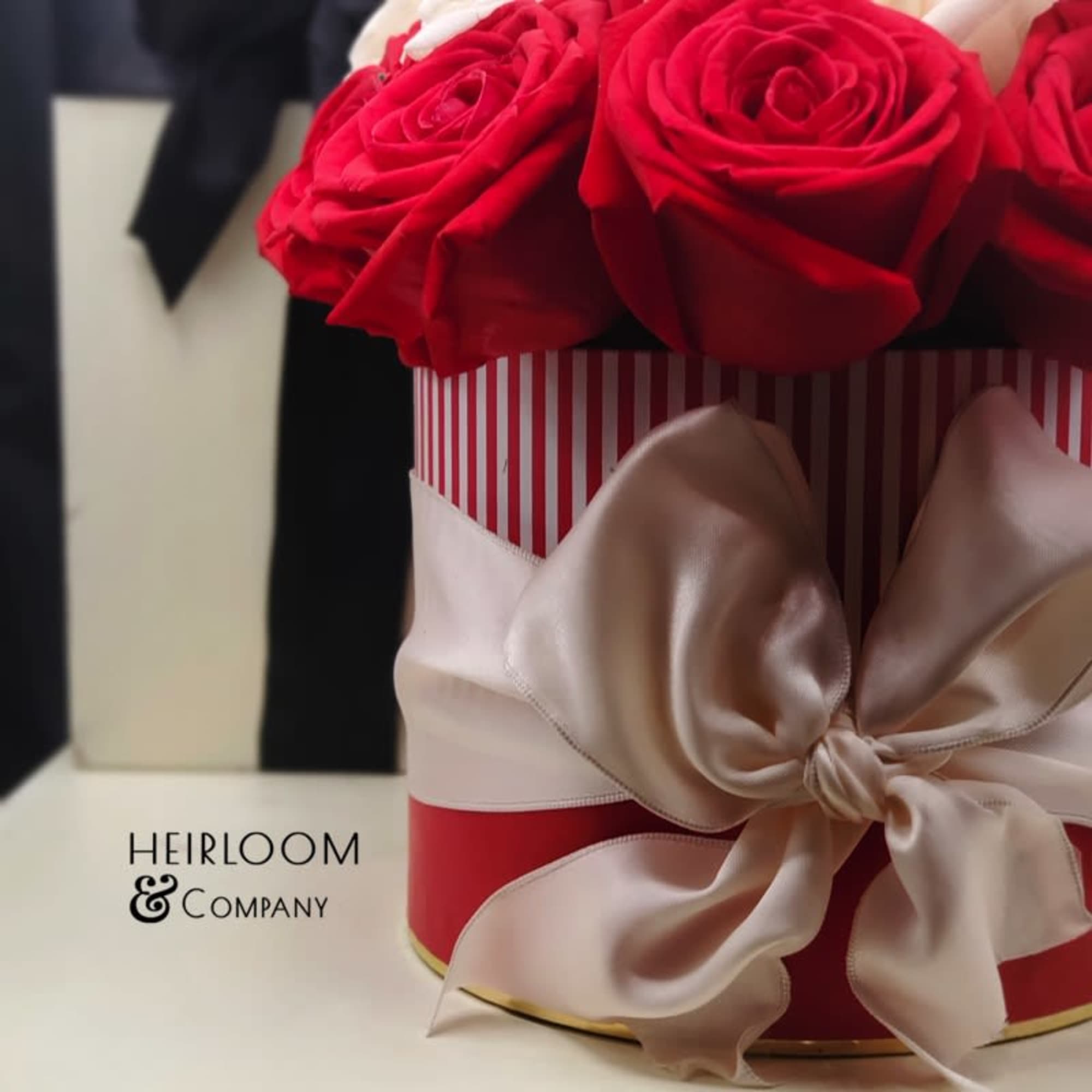 Red roses arranged in a striped gift box with a satin bow.