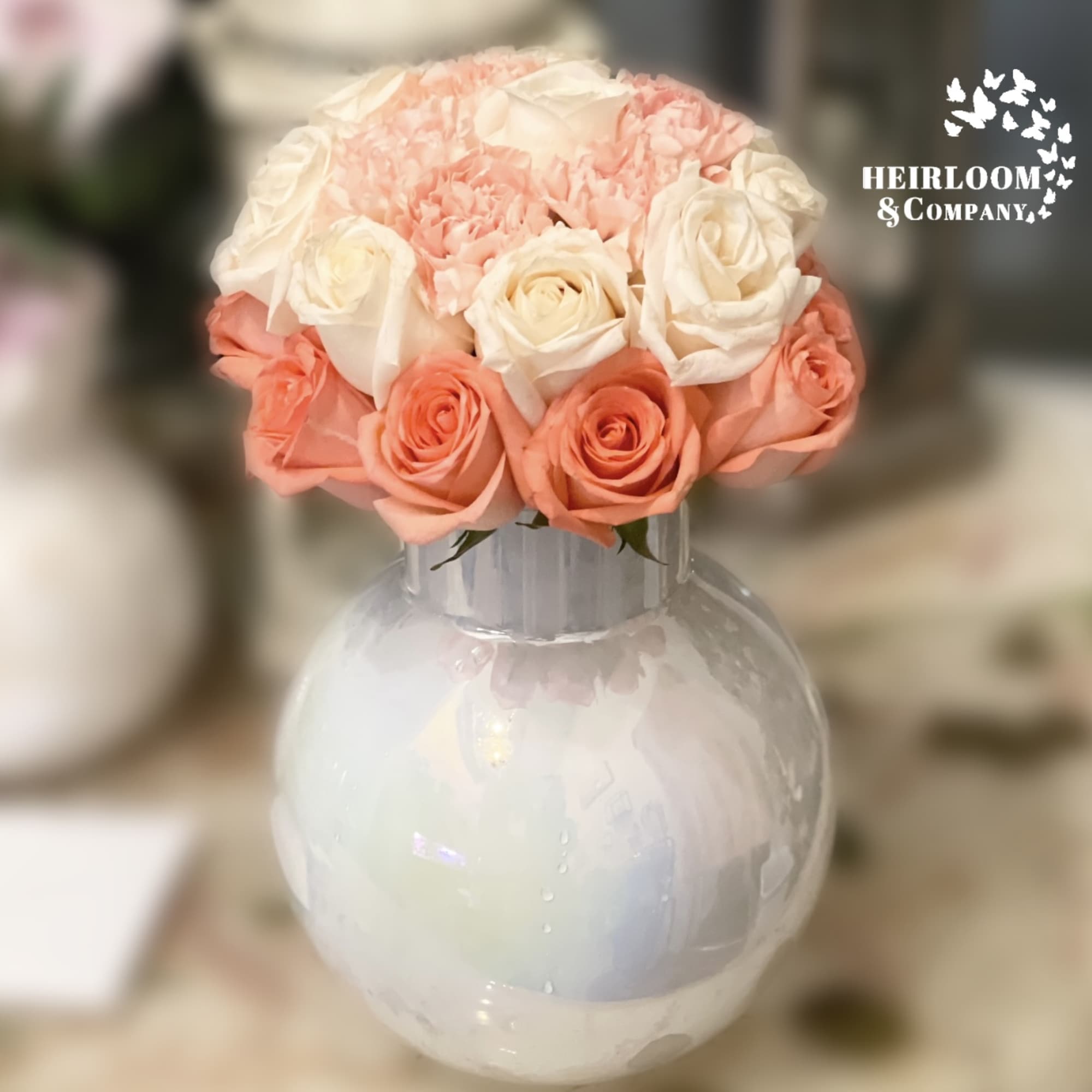 Pink and white roses arranged in a round glass vase