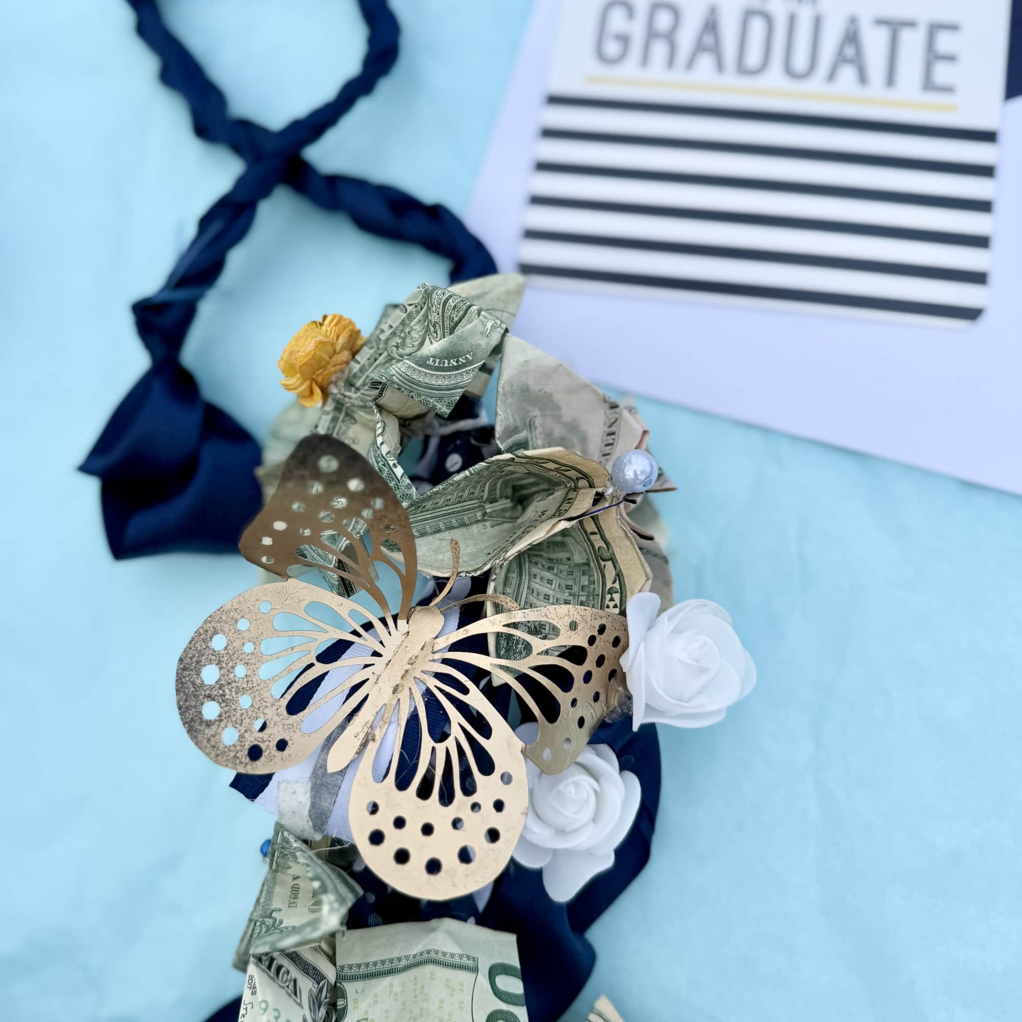 Money lei with white roses and a graduation card