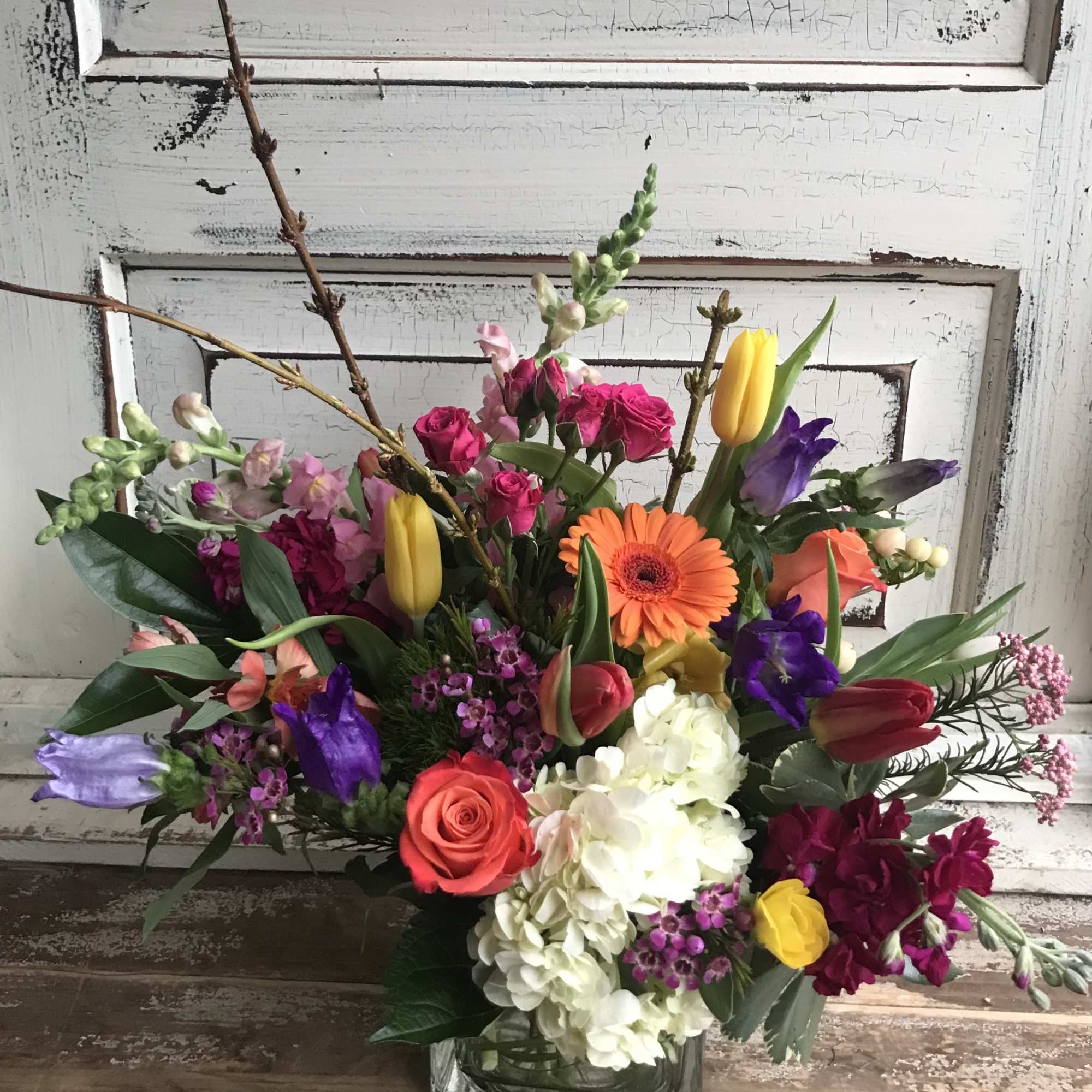 Mixed bouquet in a square glass vase with roses, tulips, hydrangeas, and gerbera daisies