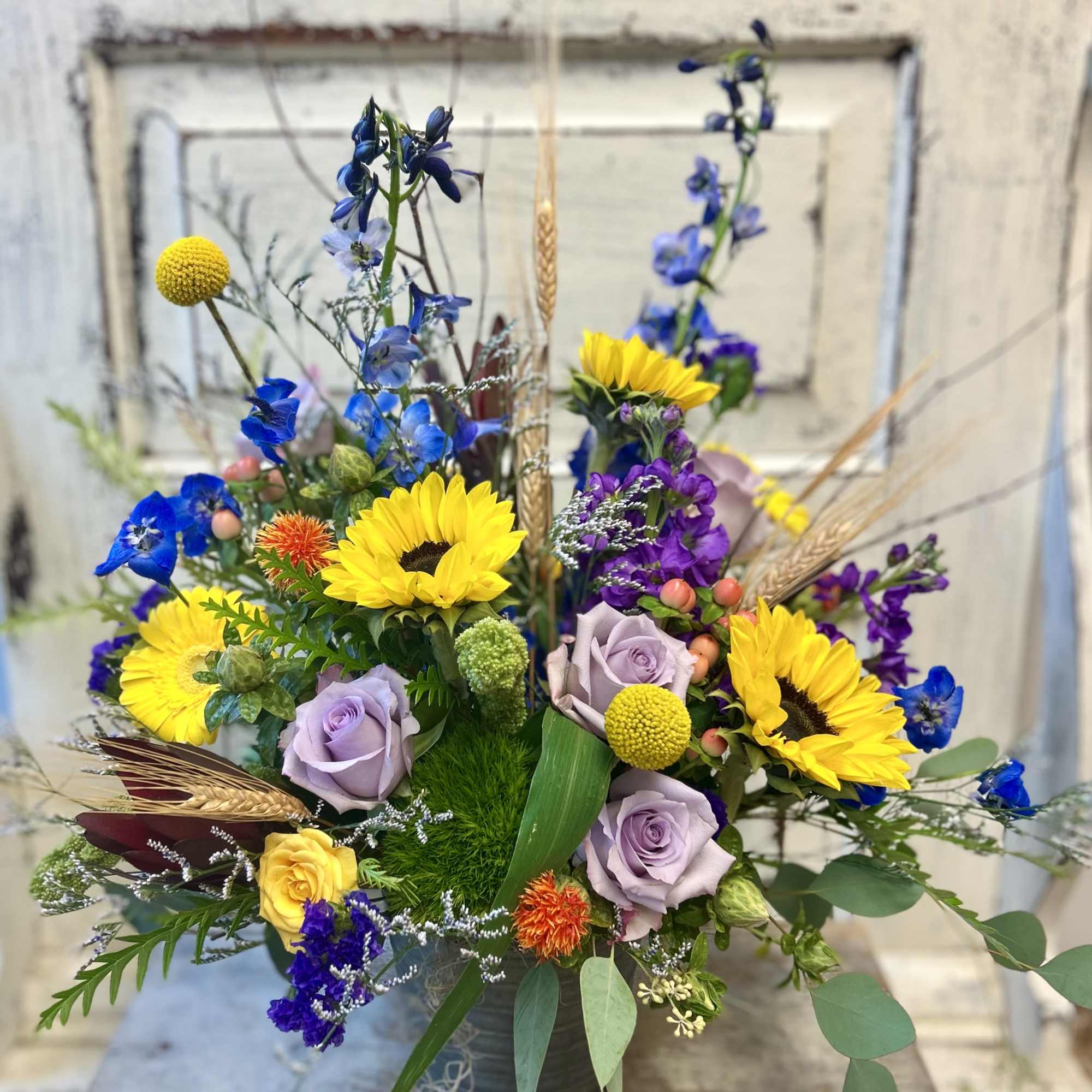Mixed bouquet with sunflowers, lavender roses, and blue flowers in a vase