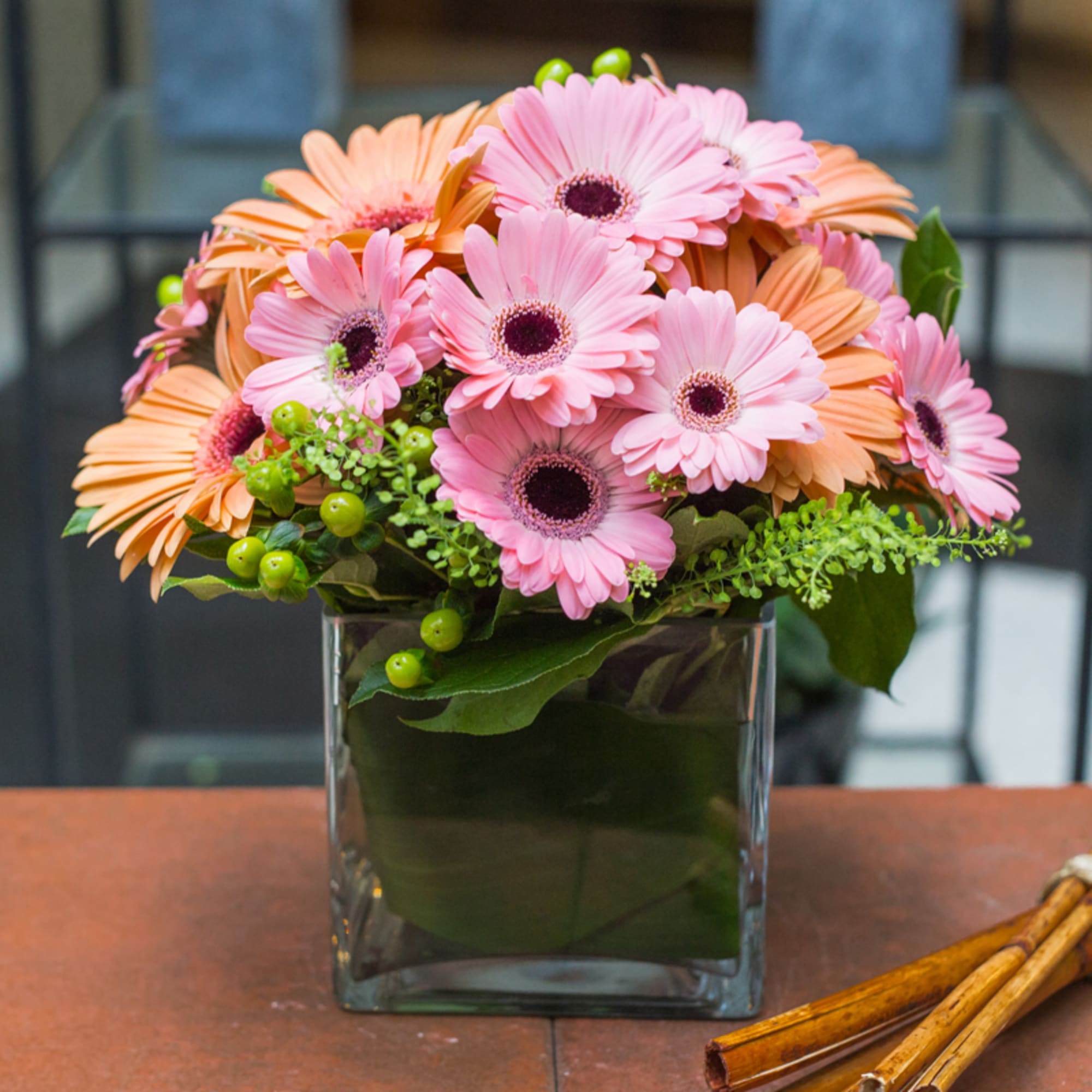 Pink and peach gerbera daisies in a square glass vase