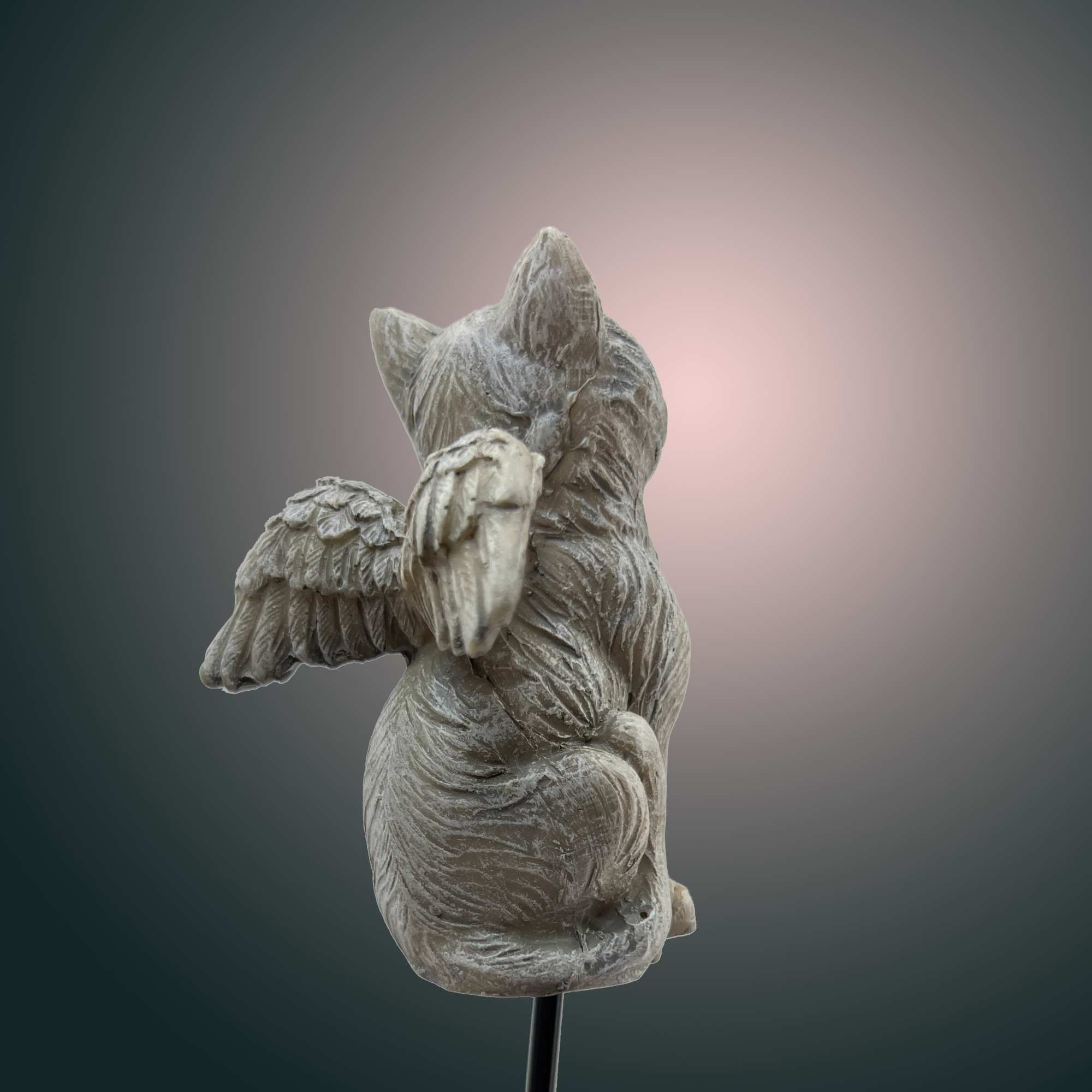 Small gray cat figurine with wings on a stand