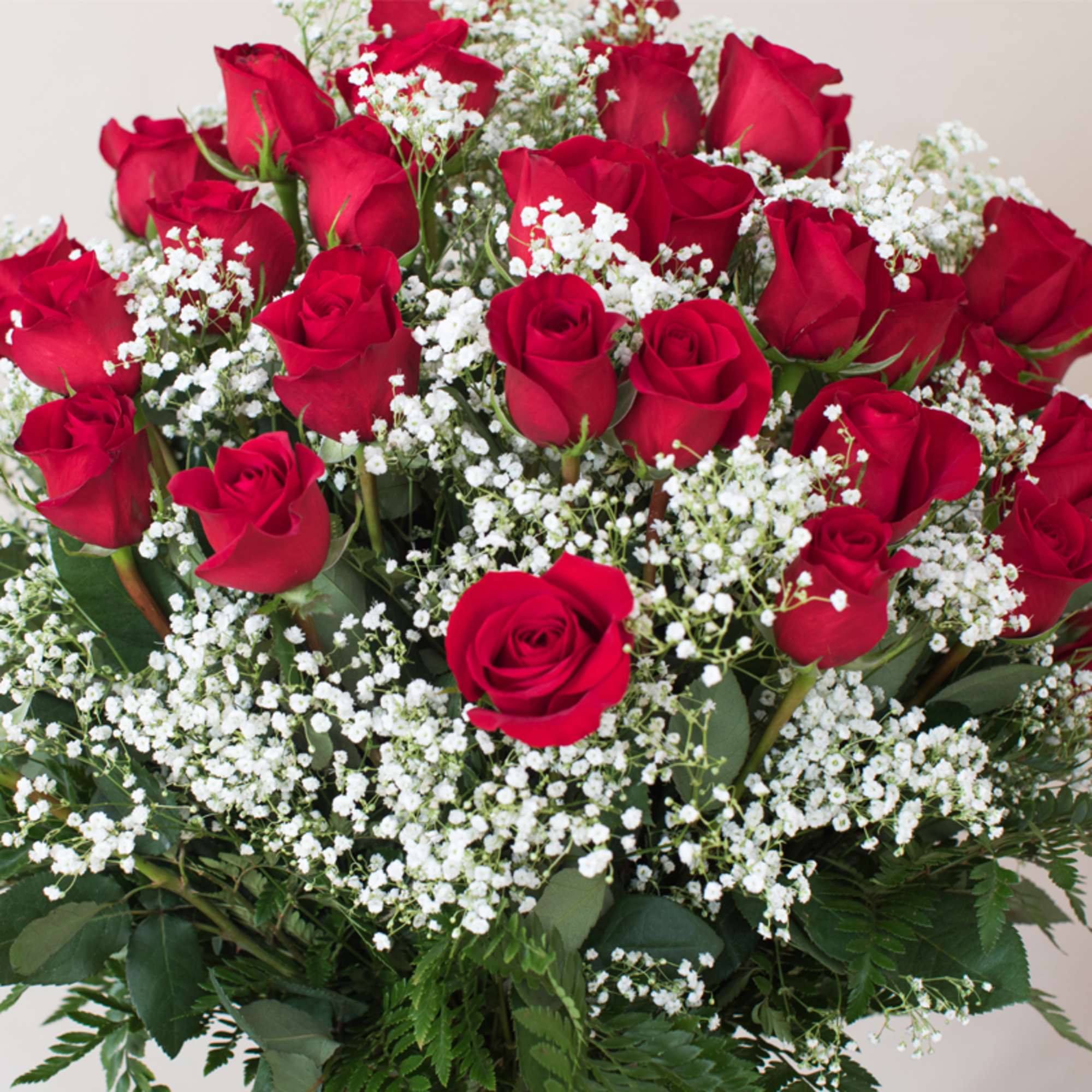 Large bouquet of red roses with white filler flowers in a dense, rounded arrangement.