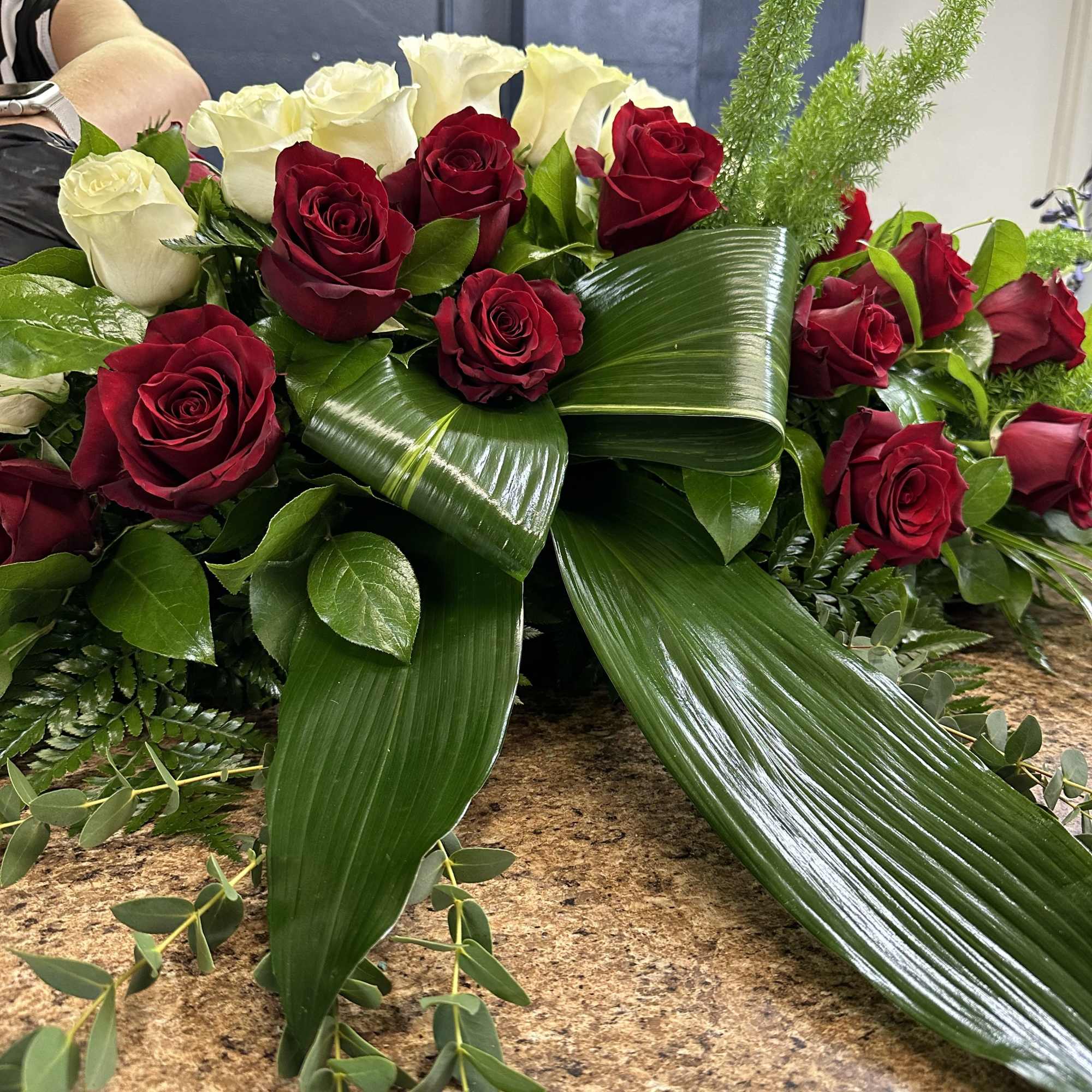 Red and white roses arranged with large glossy leaves