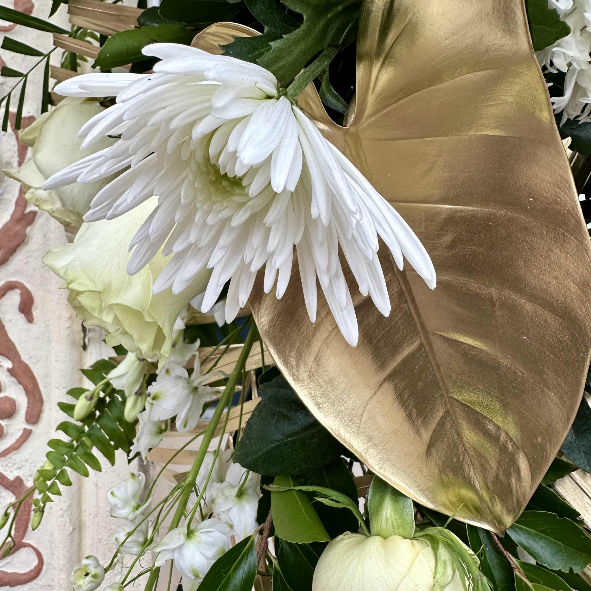White flowers with a large gold leaf accent in a floral arrangement