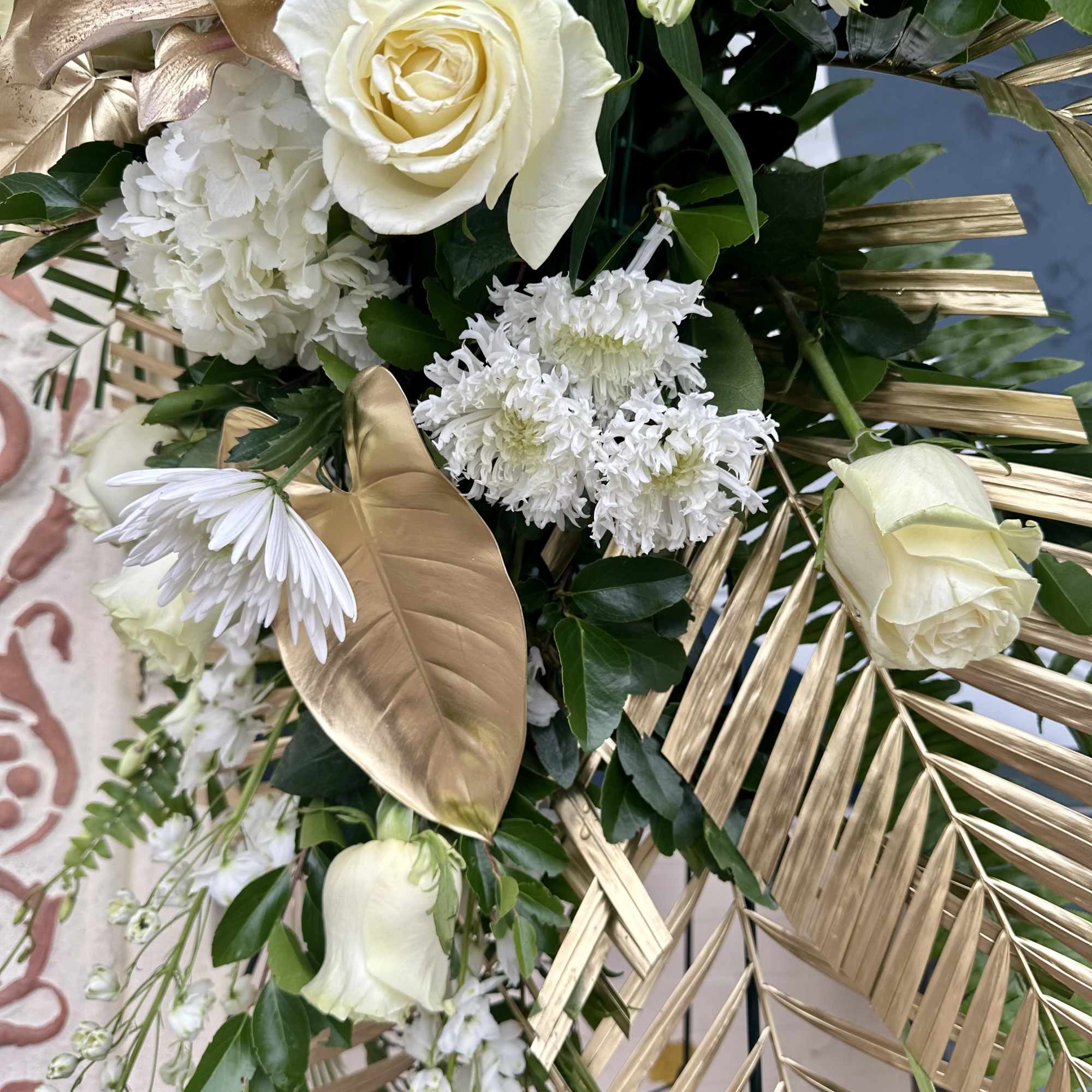 White roses and chrysanthemums with gold palm leaves in a bouquet