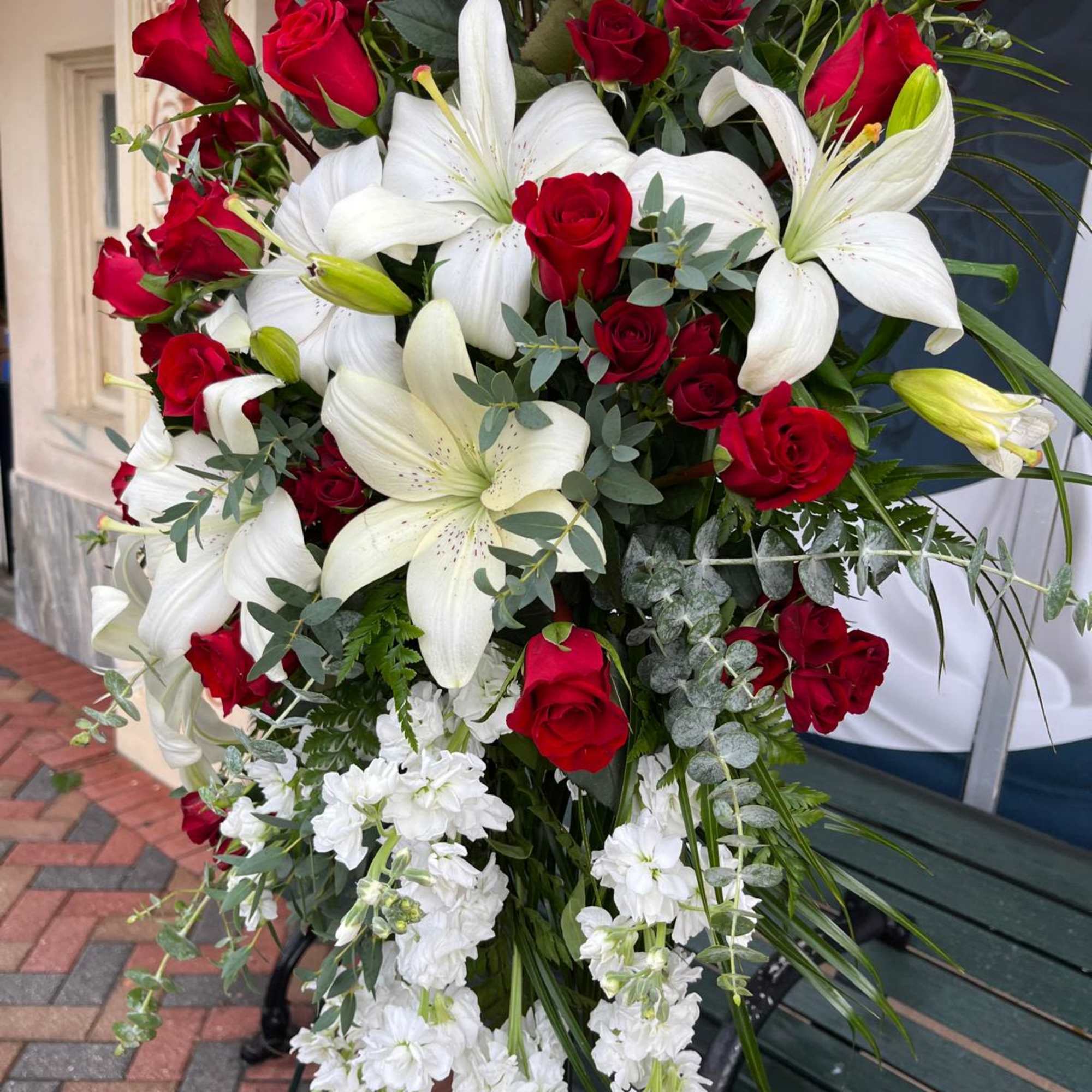 Large red rose and white lily arrangement with cascading white flowers