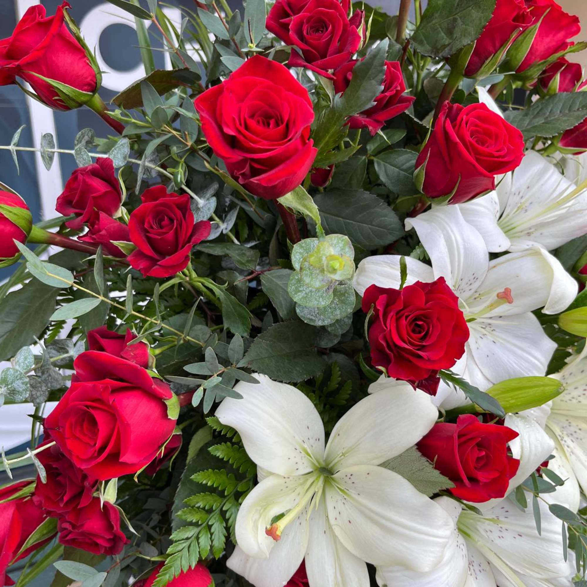 Bouquet of red roses and white lilies with mixed greenery