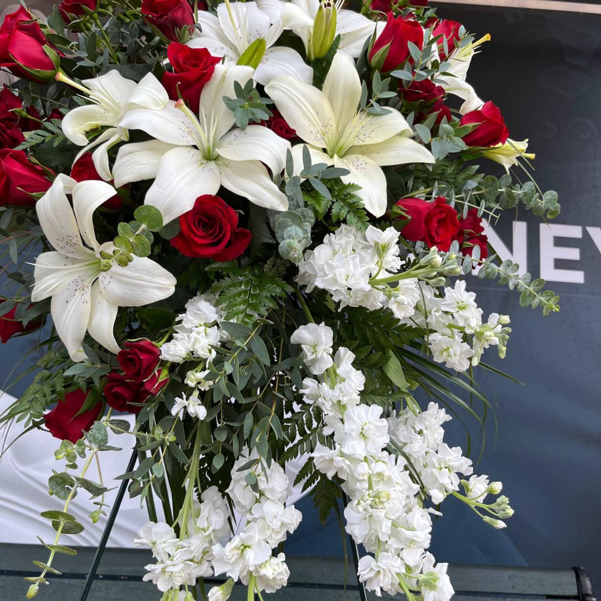Standing floral spray with red roses, white lilies, and cascading white blooms