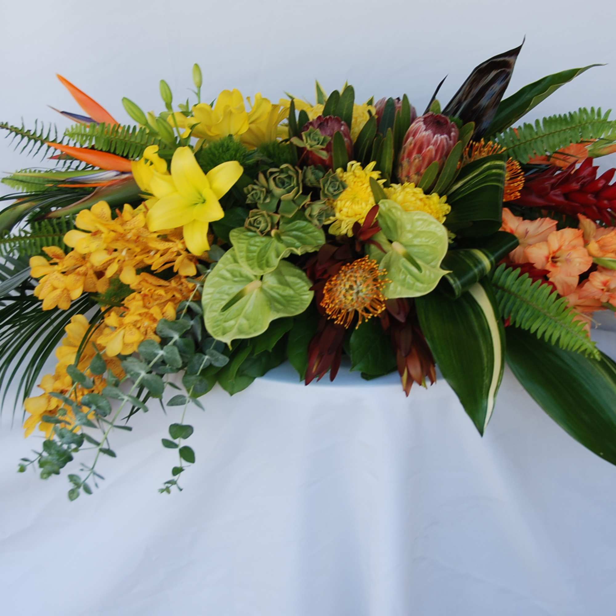 Tropical floral arrangement with yellow, orange, red, and green blooms
