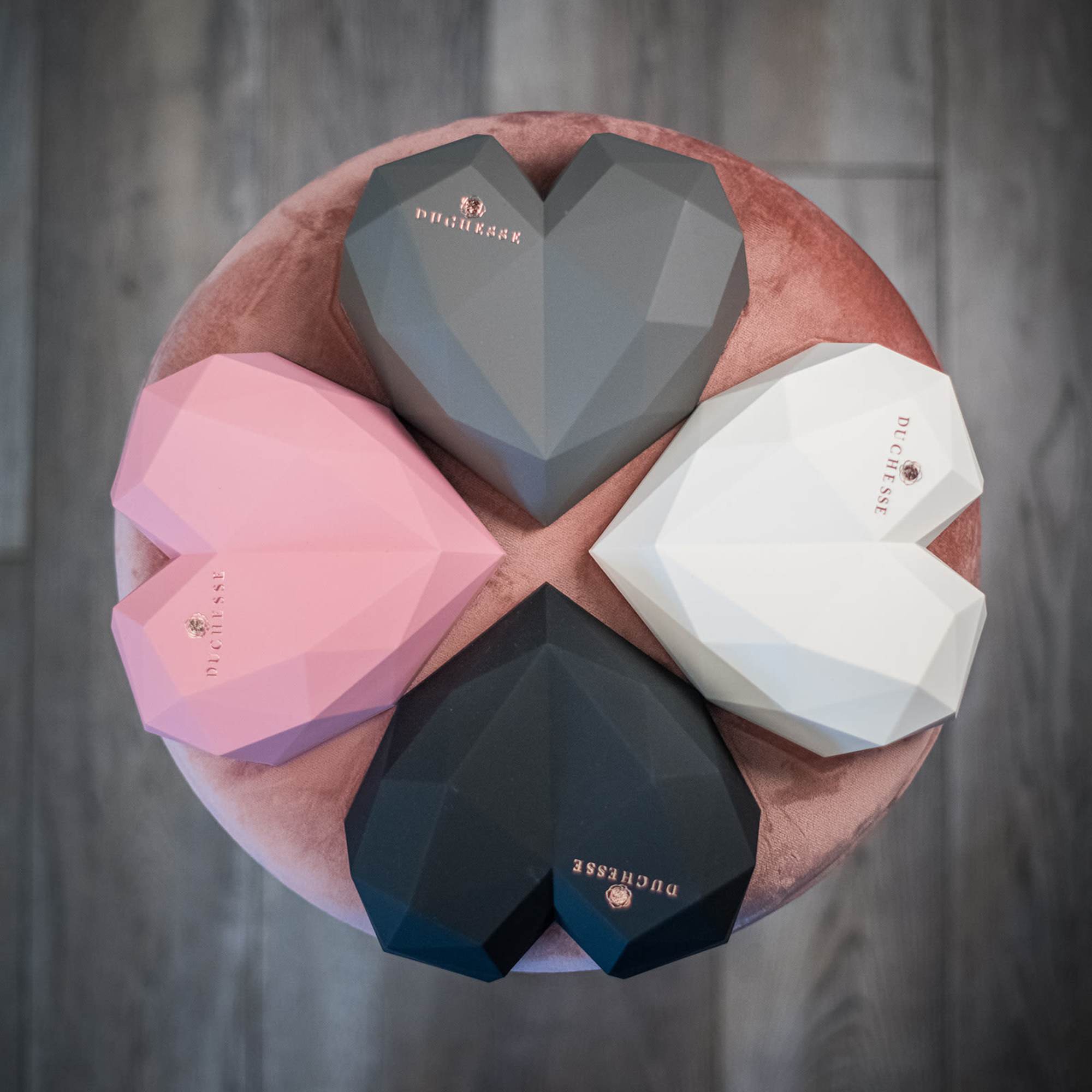 Four heart-shaped gift boxes on a round pink velvet surface