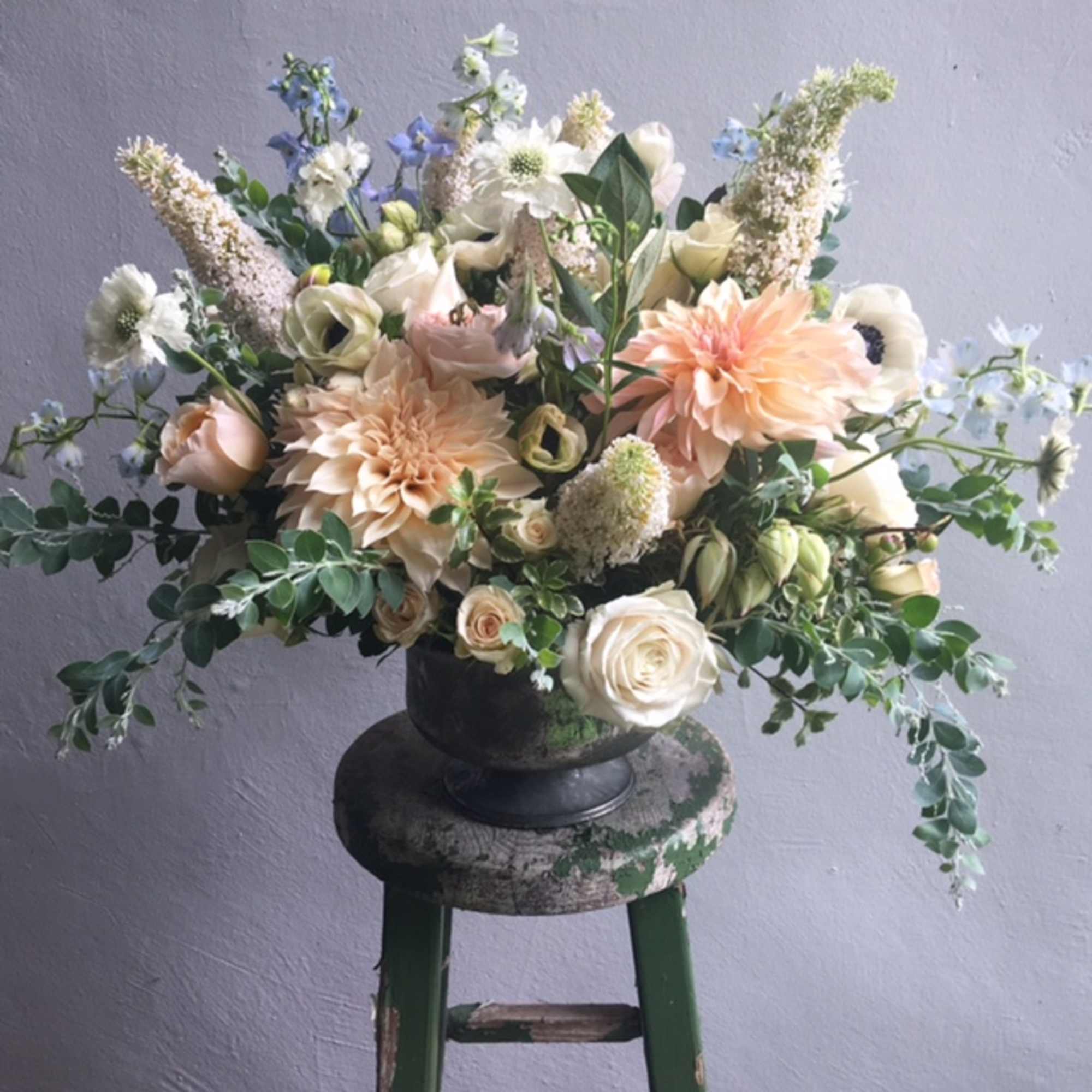 Large pastel floral arrangement in a dark urn vase