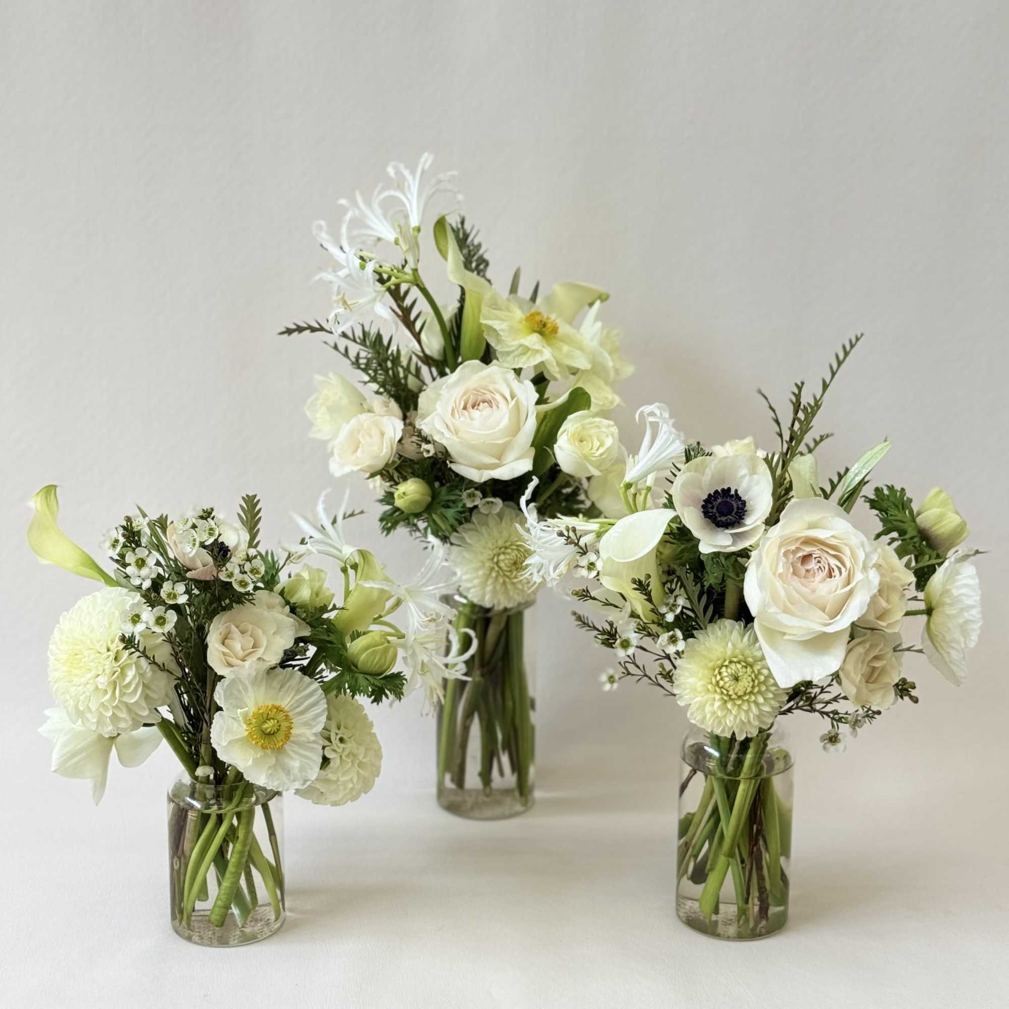 Three white floral arrangements in clear glass vases