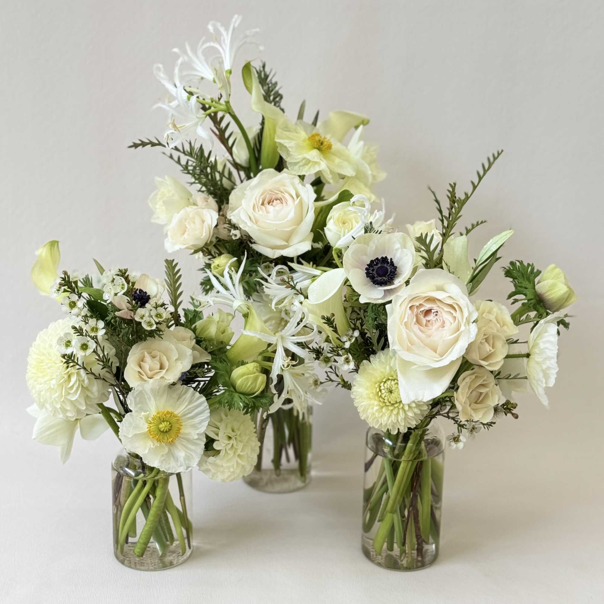 Three white floral arrangements in clear glass vases, photo 2 of 2