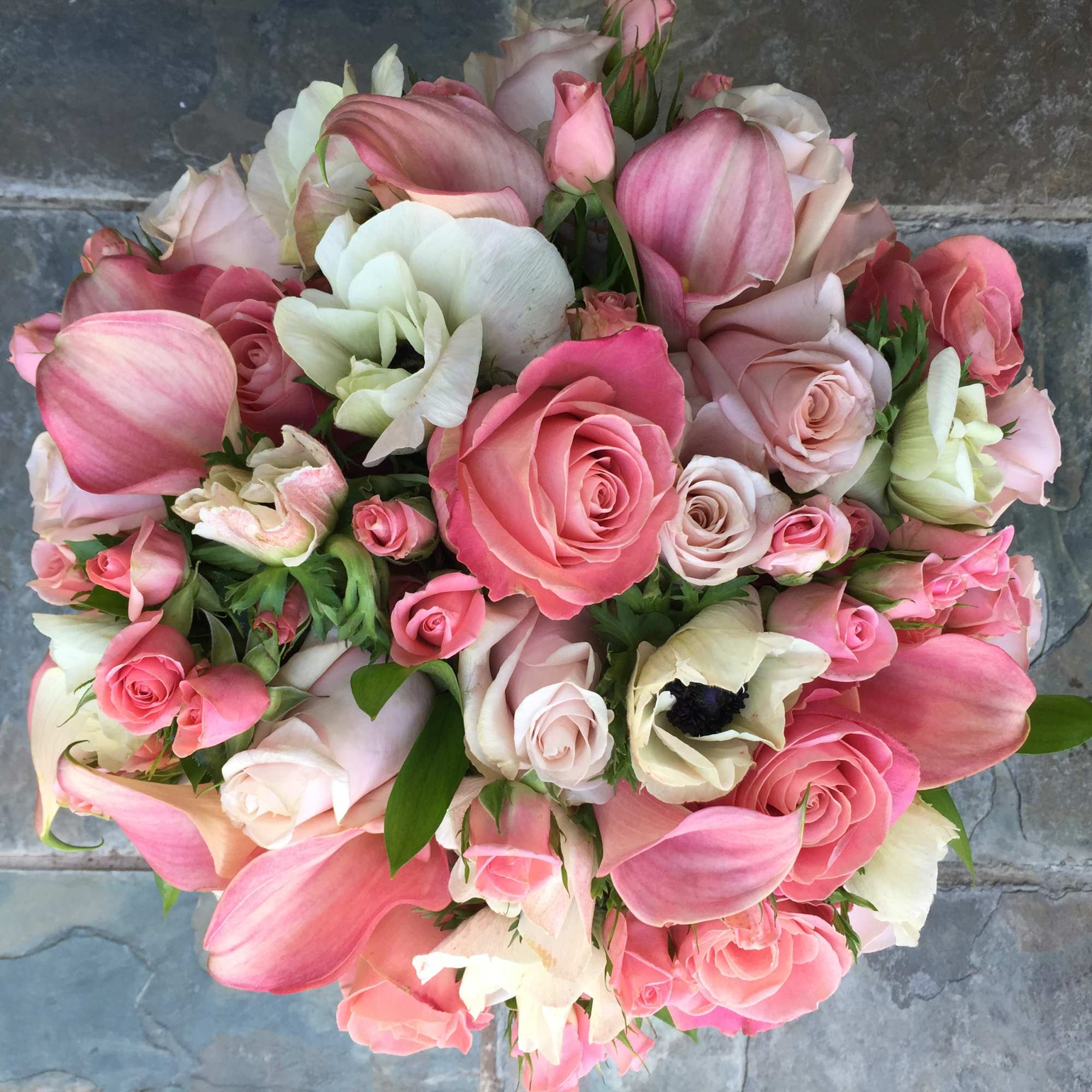 Round bouquet of pink roses and calla lilies with white blooms viewed from above