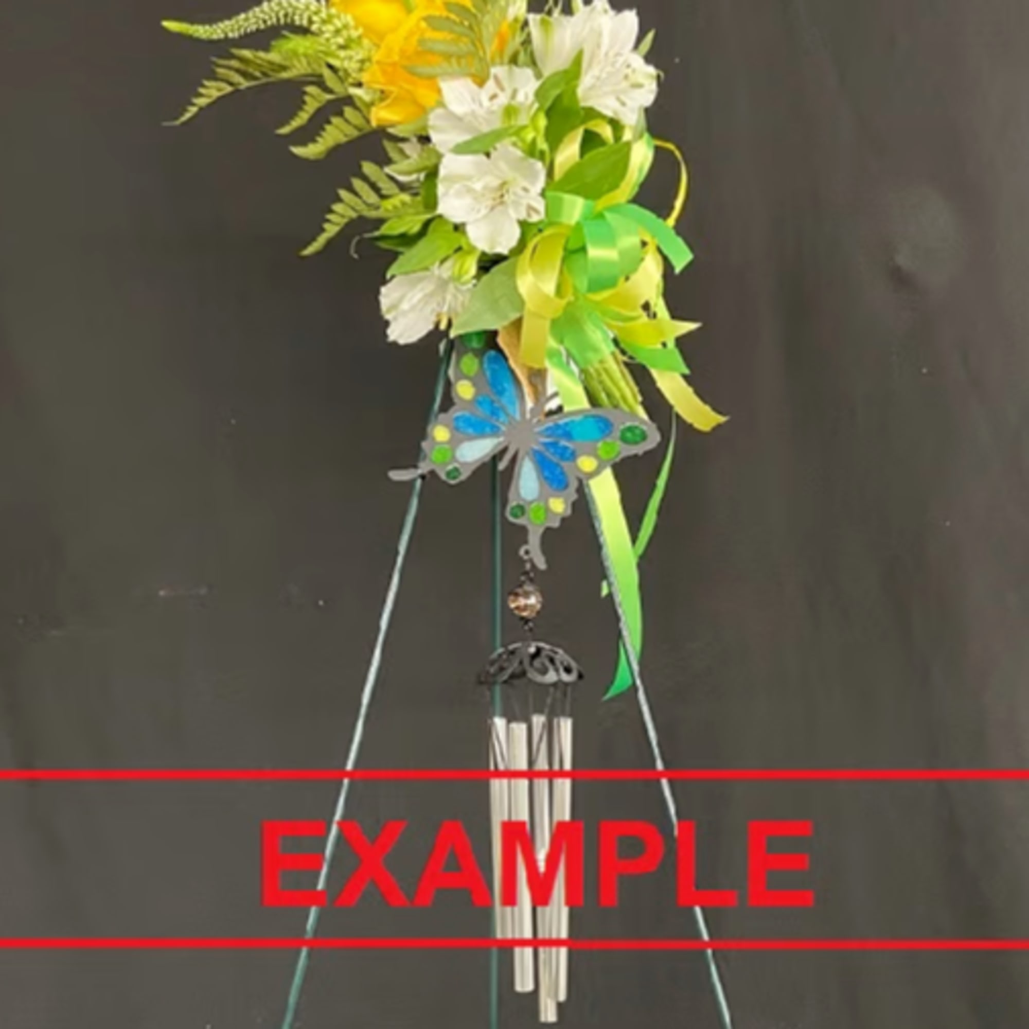Tall wind chime on a stand topped with yellow and white flowers, green ribbons, and a blue butterfly accent