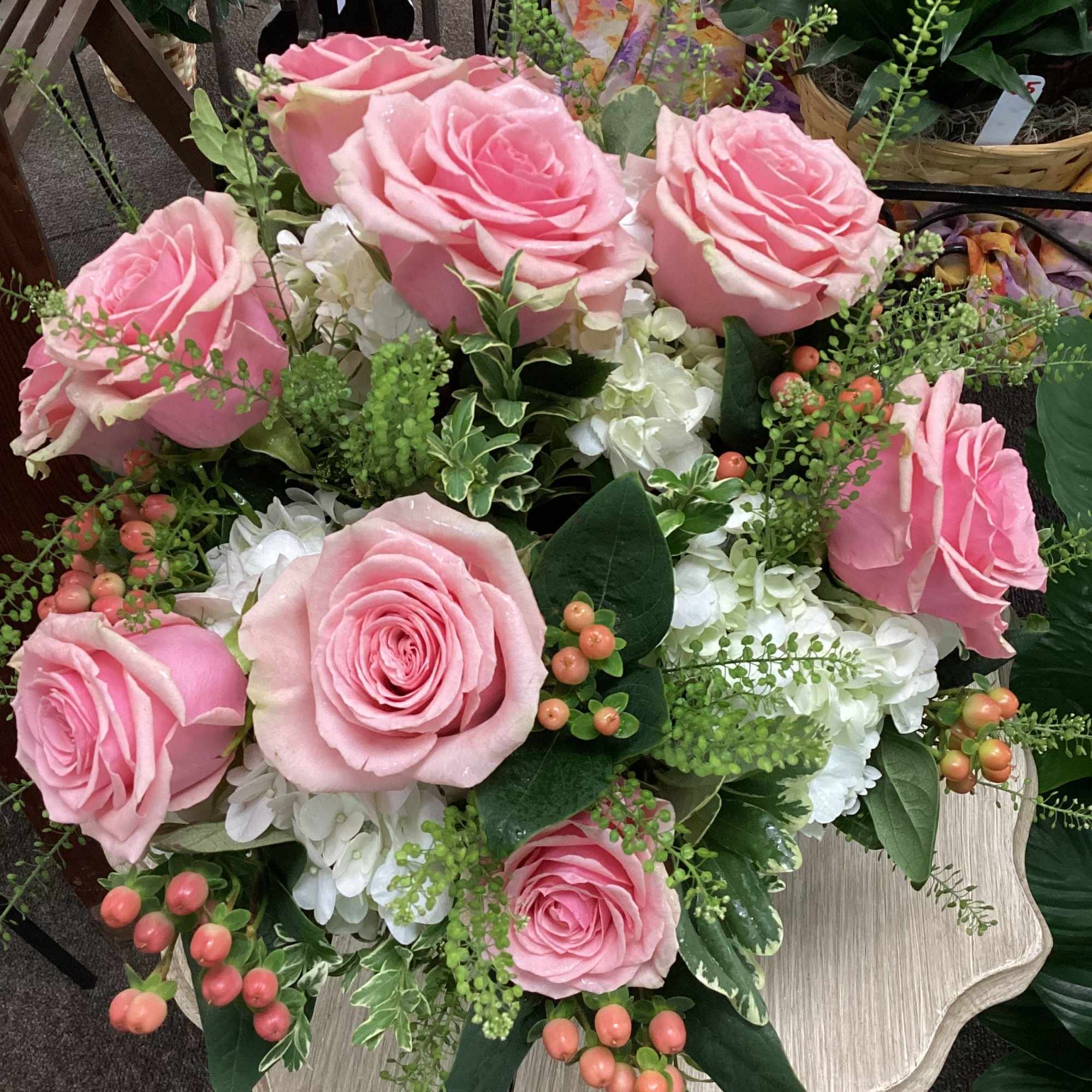Low arrangement of pink roses, white hydrangeas, and peach berries in a compact design