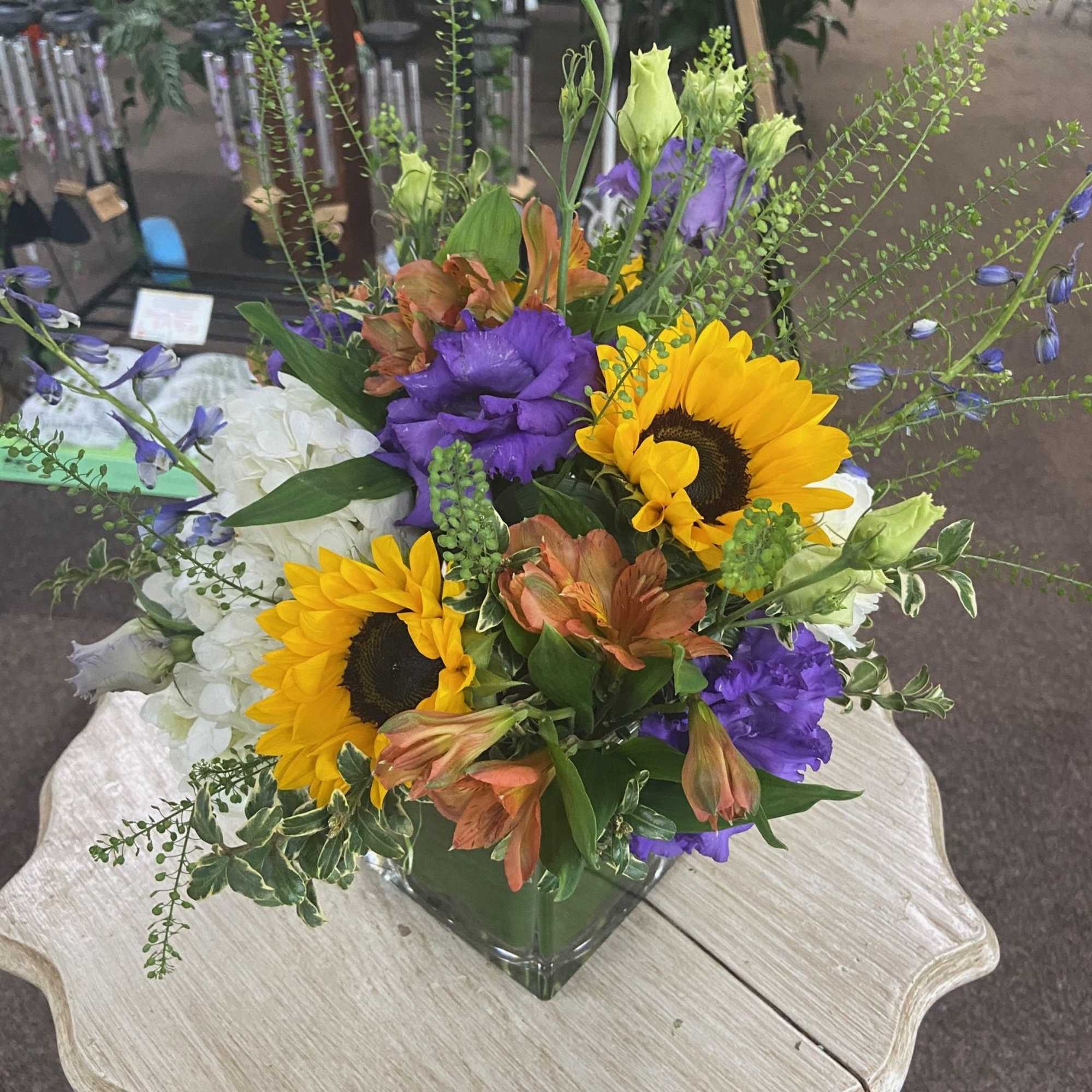 Sweetness roses, purple lisianthus, fluffy white hydrangeas, piercing blue delphinium, and yellow
