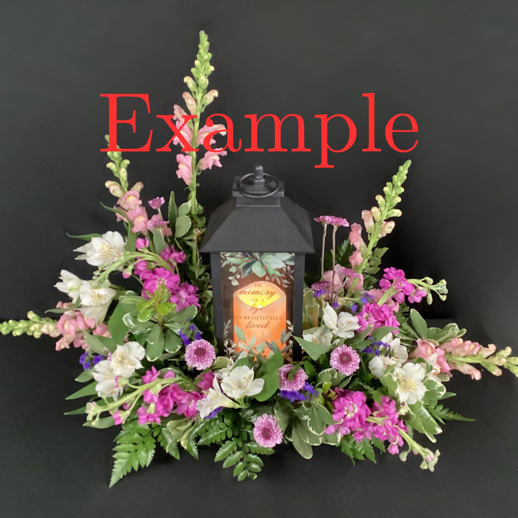 Sympathy lantern centerpiece with pink and white flowers around a black memorial lantern.