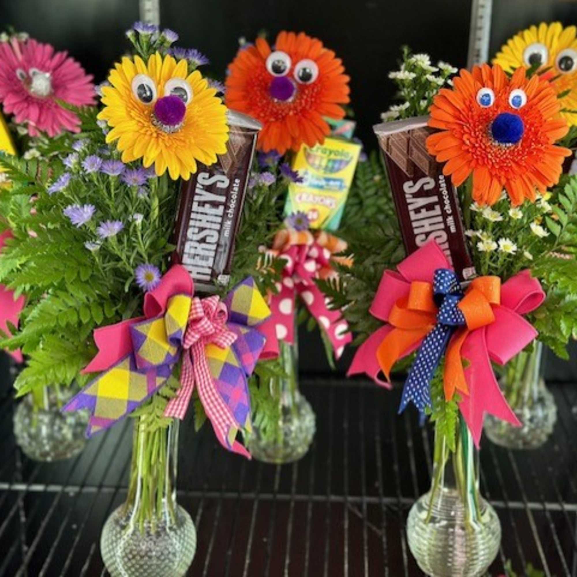 Colorful flower bouquets with candy bars and bows in glass vases