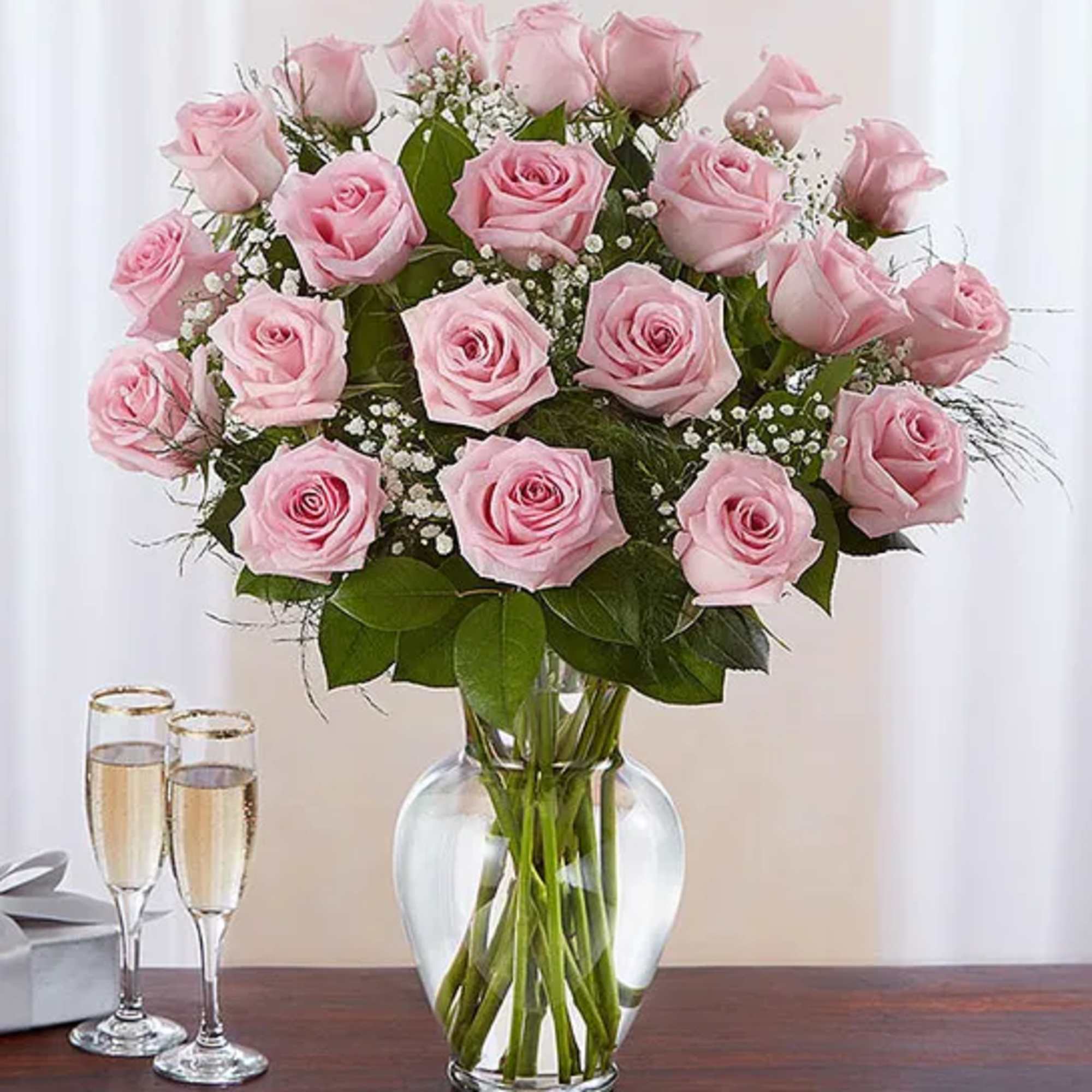 Pink roses arranged in a clear glass vase with baby's breath