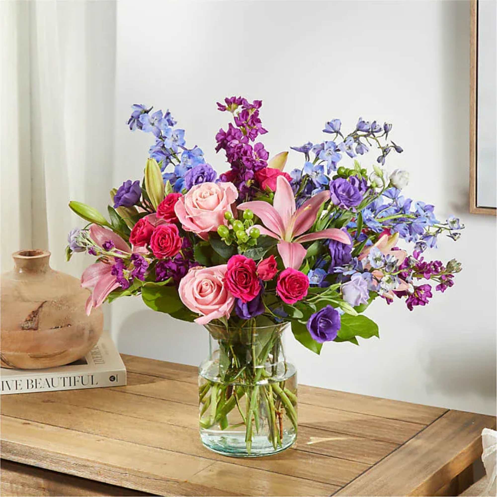 Mixed bouquet of pink, purple, and blue flowers in a glass vase
