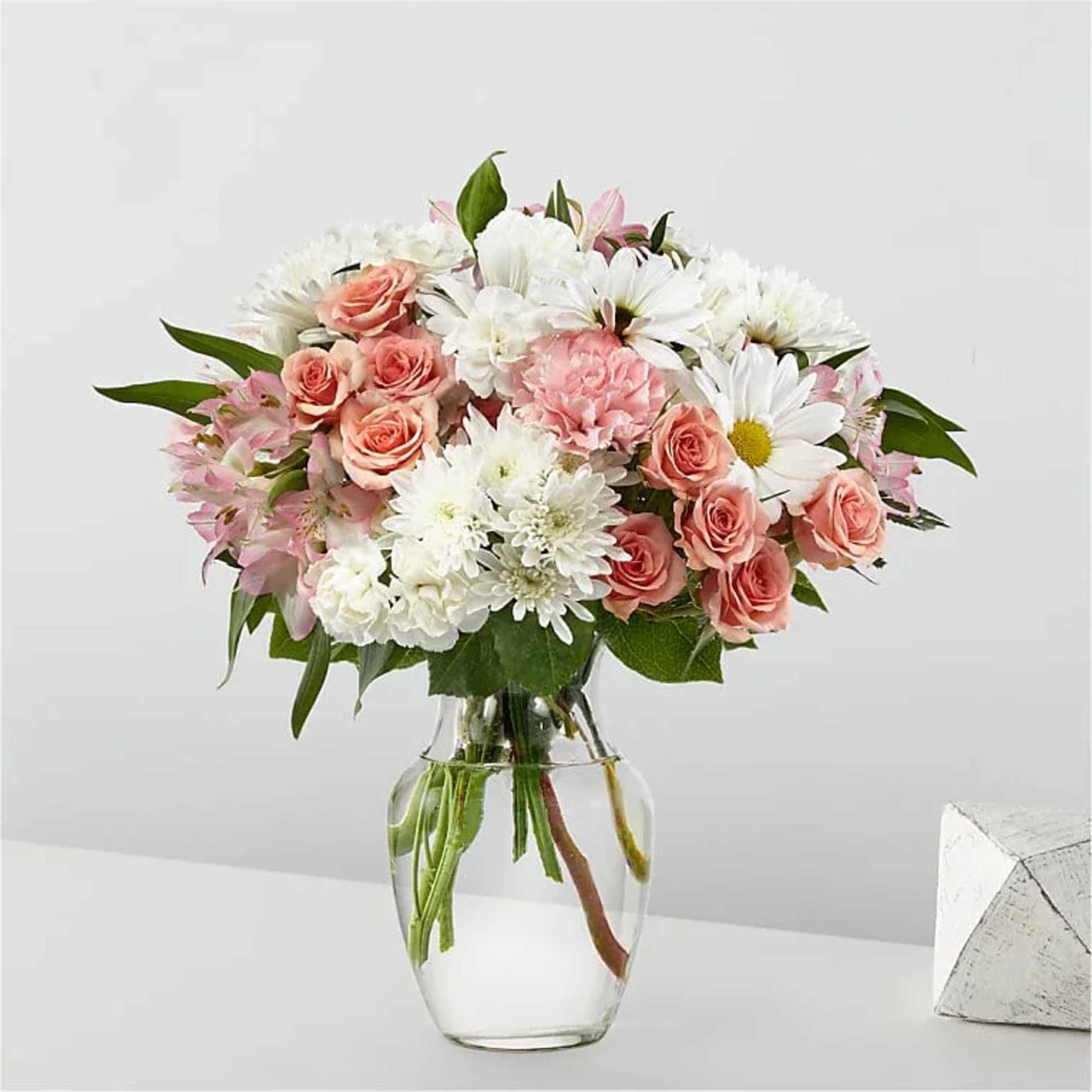 Pink roses and white daisies in a clear glass vase