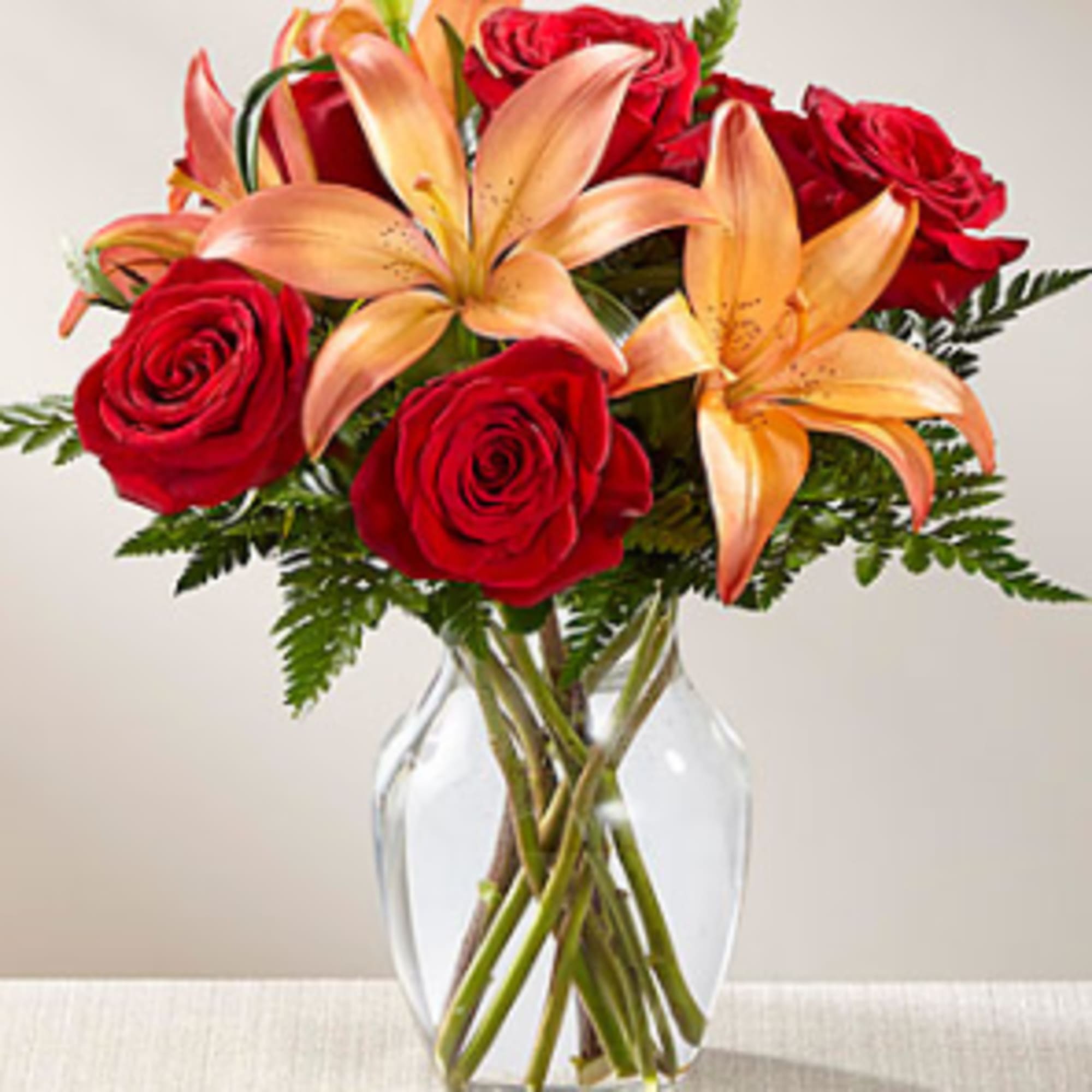 Rich red roses are paired with orange Asiatic Lilies to create a