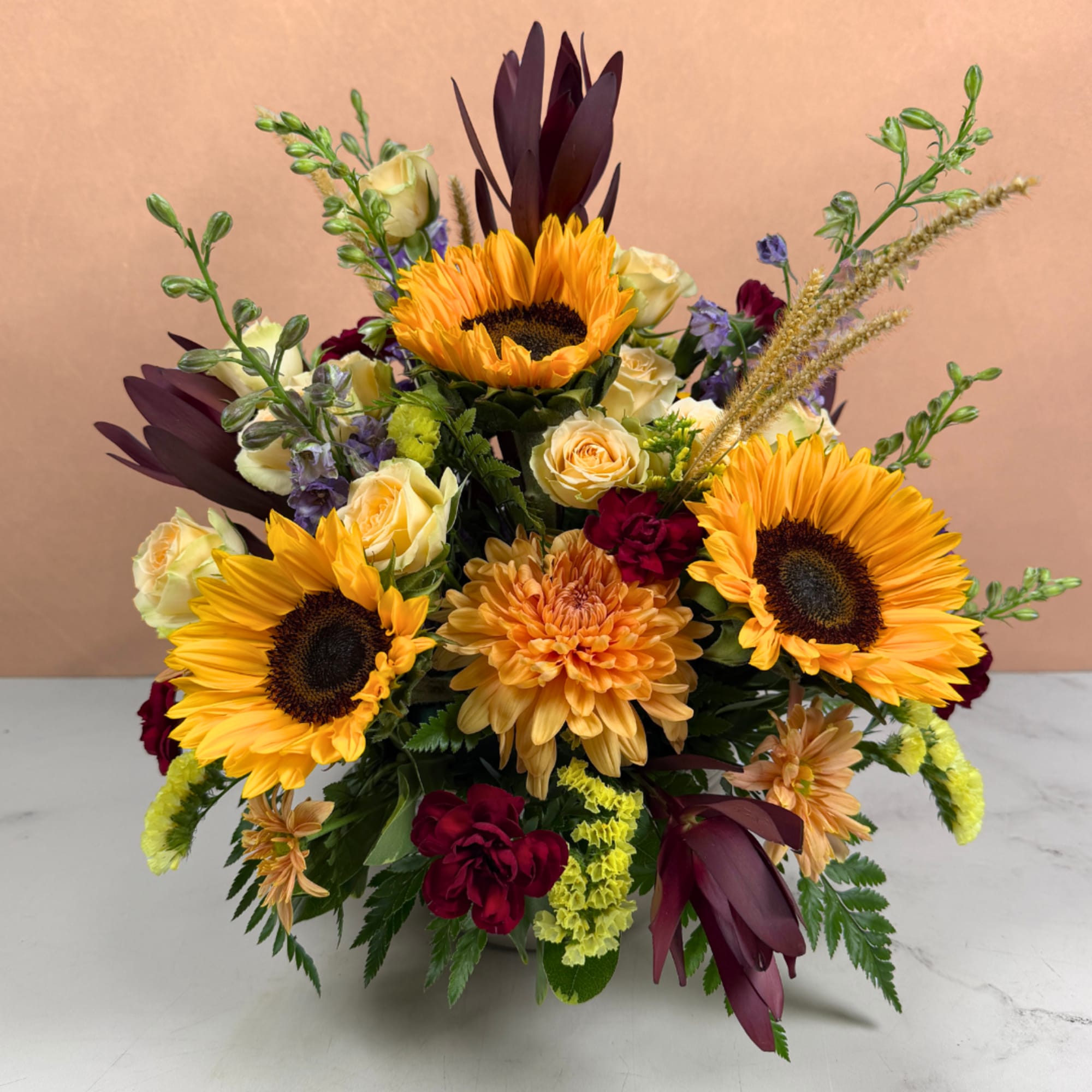 Mixed bouquet with sunflowers, roses, and chrysanthemums in a low container