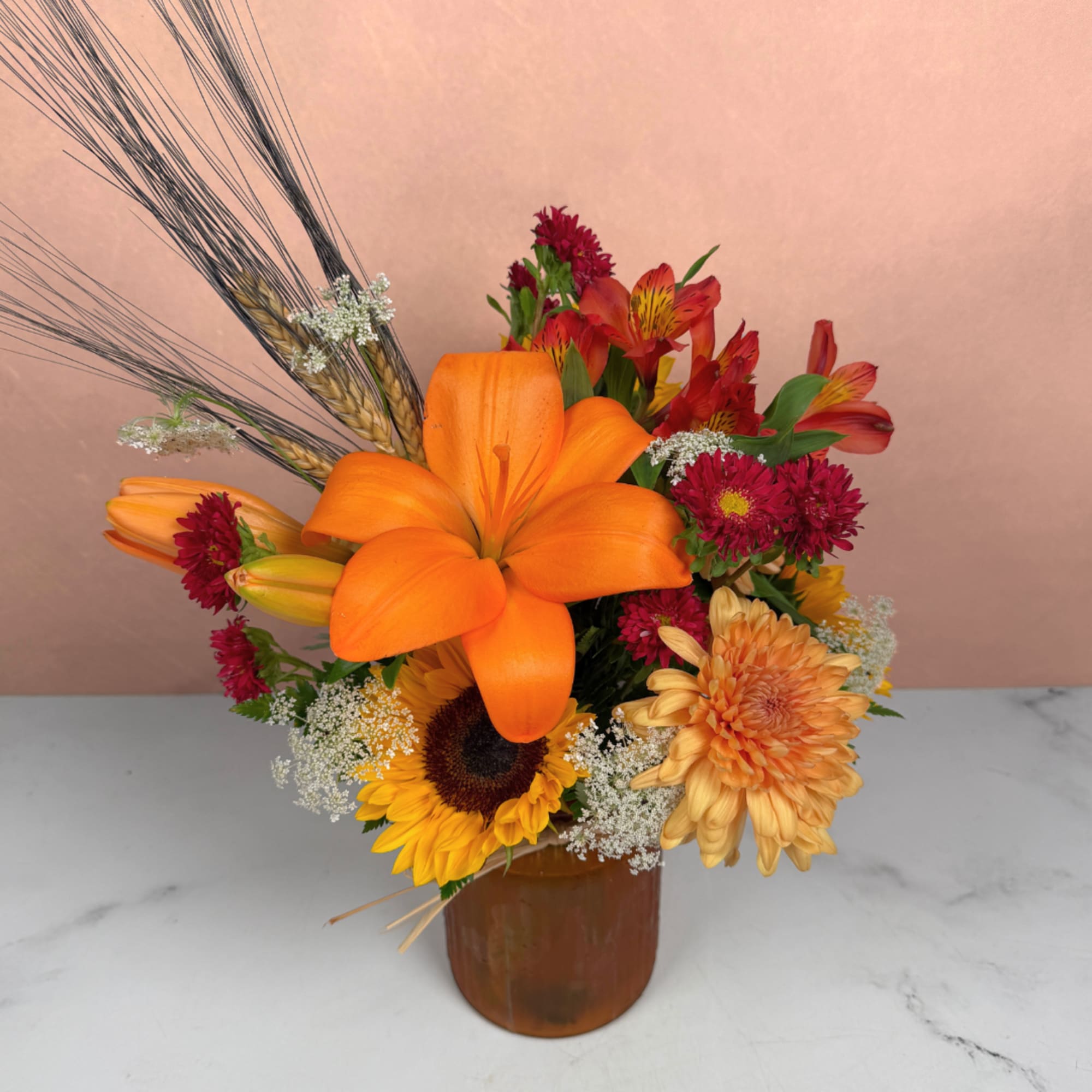 Orange lily bouquet with sunflowers and chrysanthemums in a brown vase