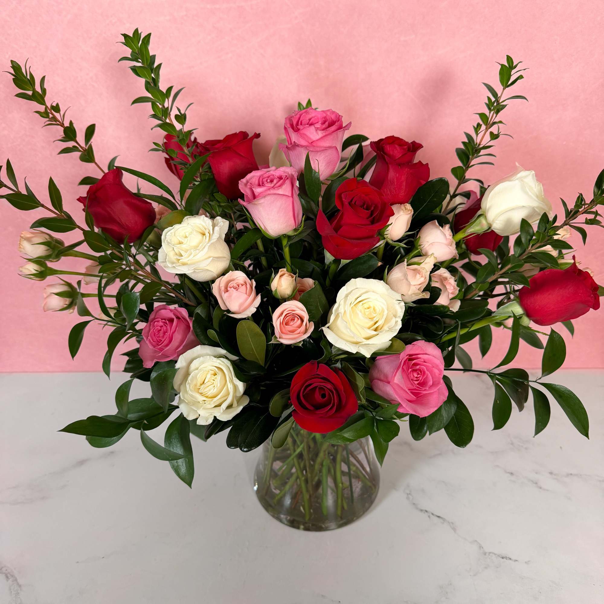 Bouquet of red, pink, and white roses in a clear glass vase
