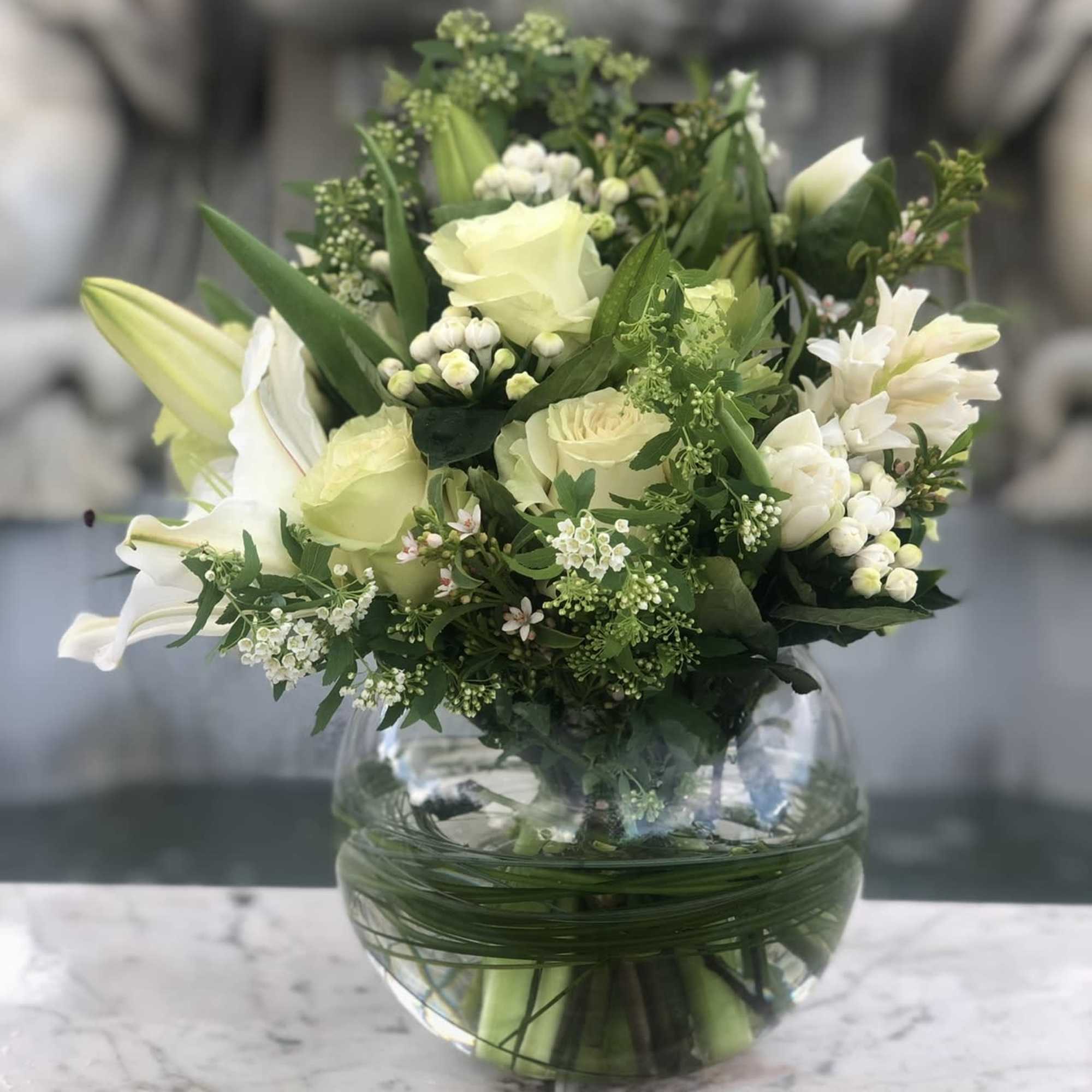 White and pale yellow bouquet in a round glass vase