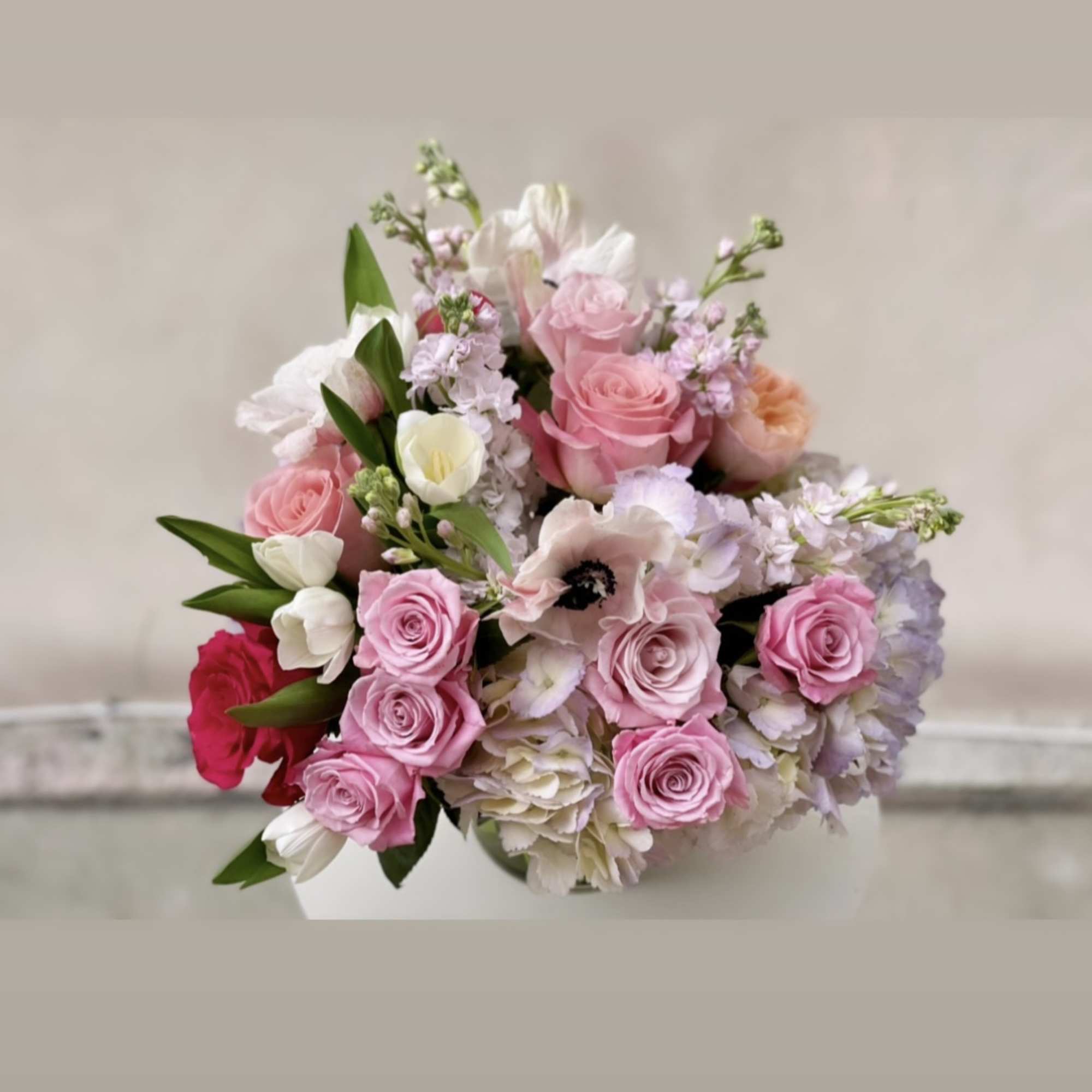 Pastel pink and white flower arrangement in a white vase.