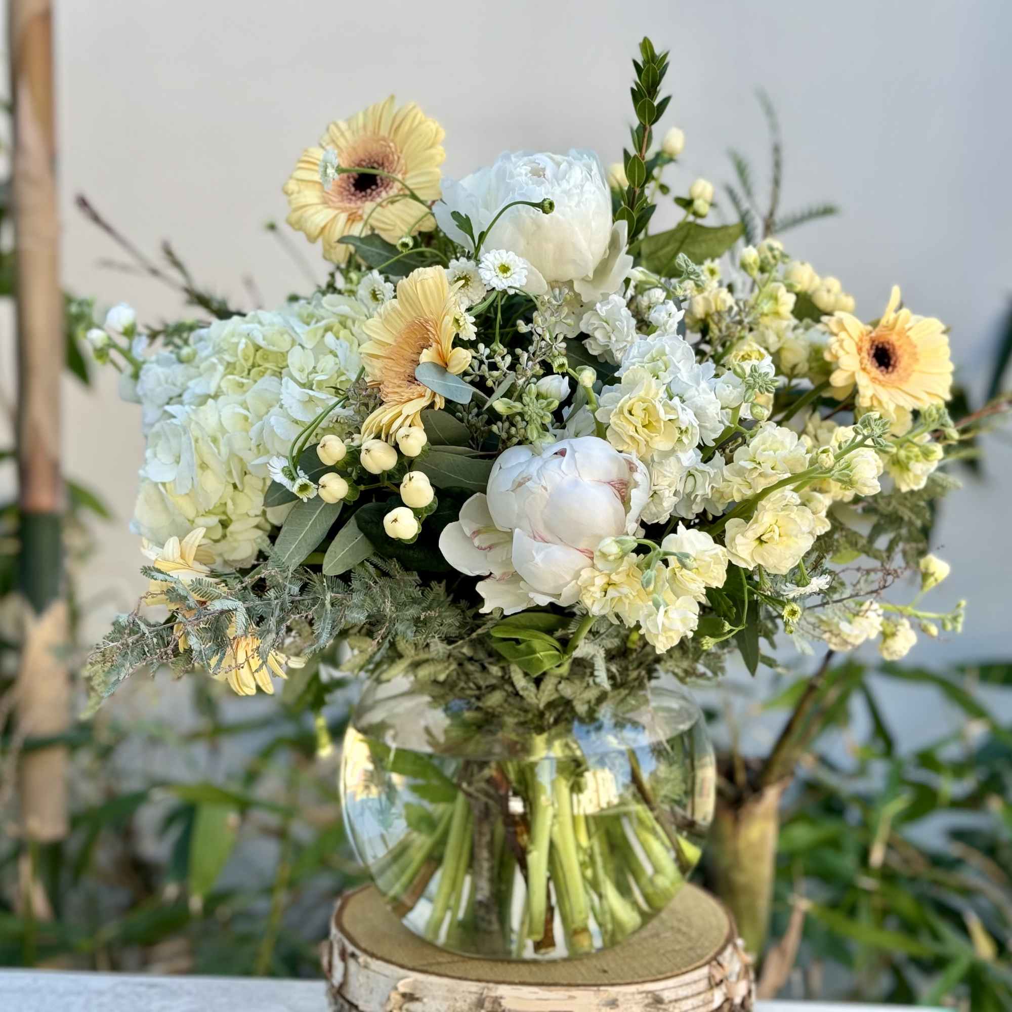 Mixed bouquet of pale yellow and white flowers in a clear glass vase