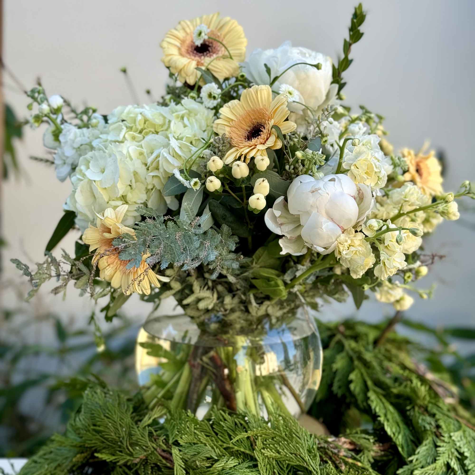 Pastel bouquet with gerbera daisies, white peonies, and hydrangeas in a glass vase