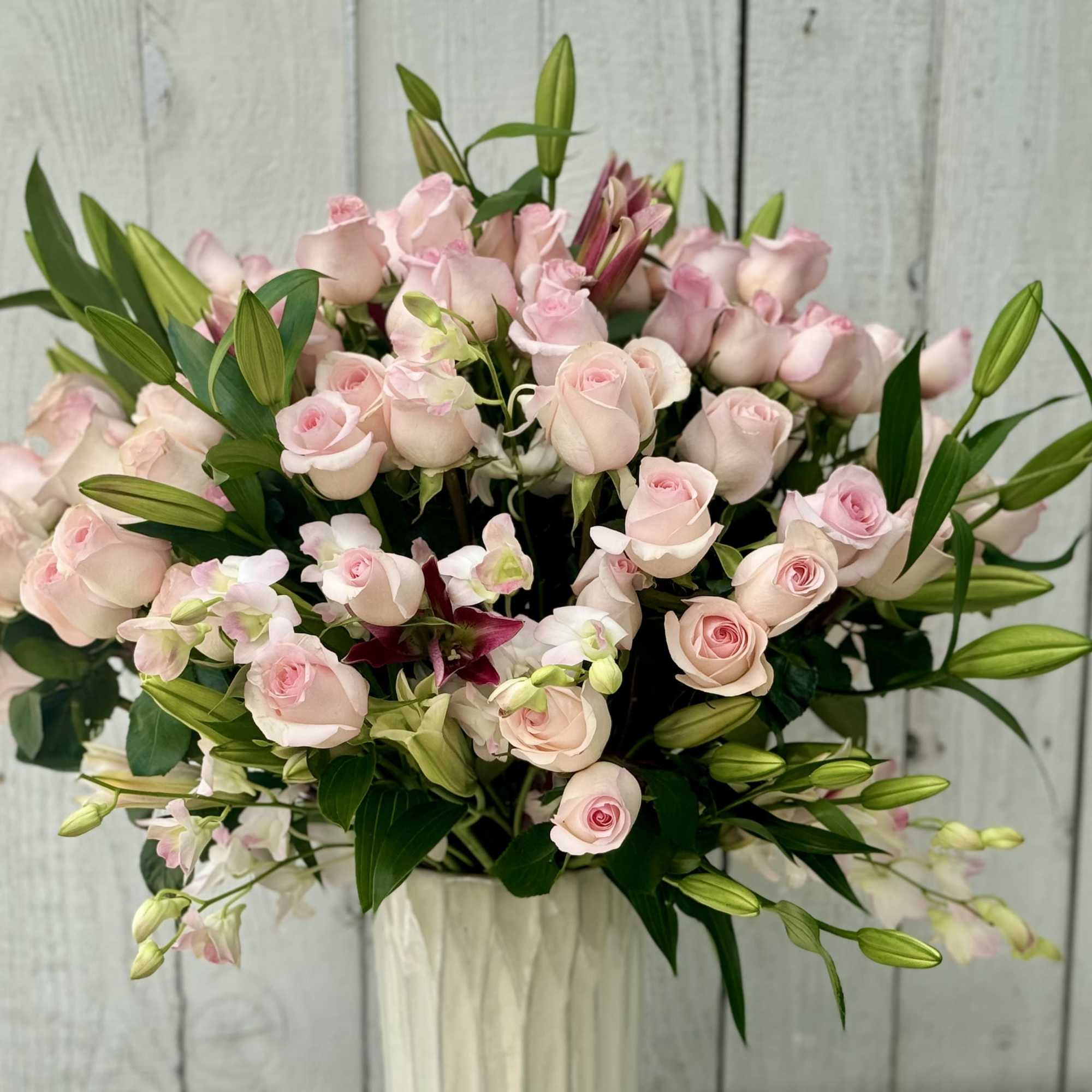 Bouquet of pale pink roses and lilies in a white vase