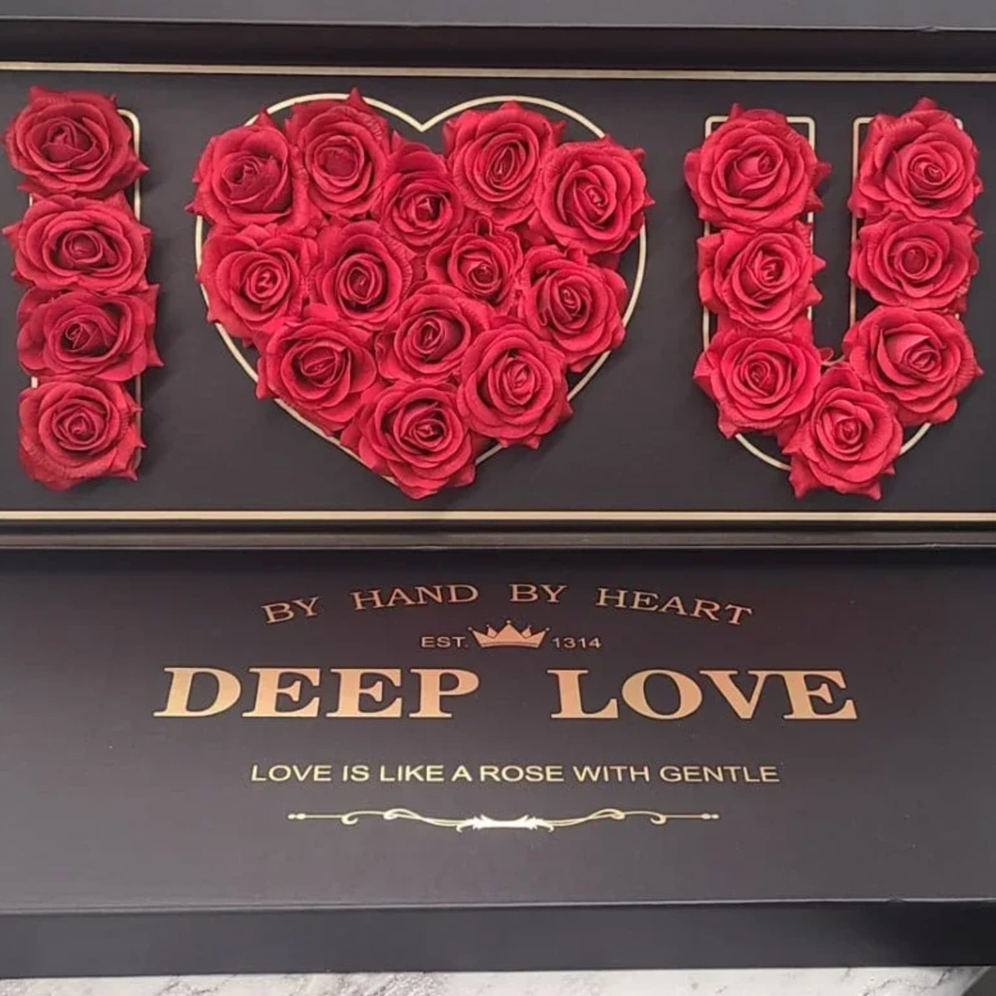 Red roses arranged to spell "I ♥ U" in a black display box
