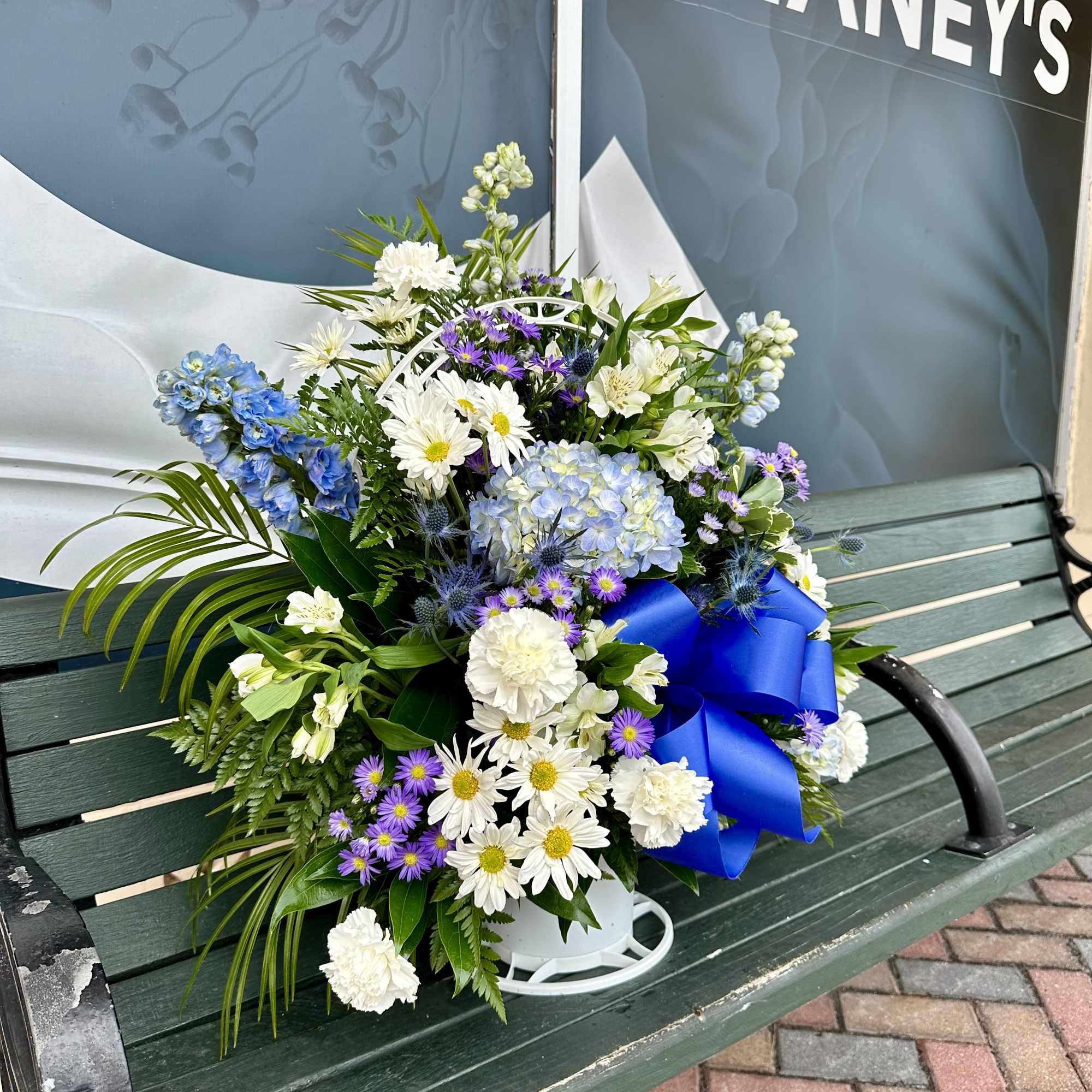 Mixed bouquet of white, blue, and purple flowers with a blue ribbon