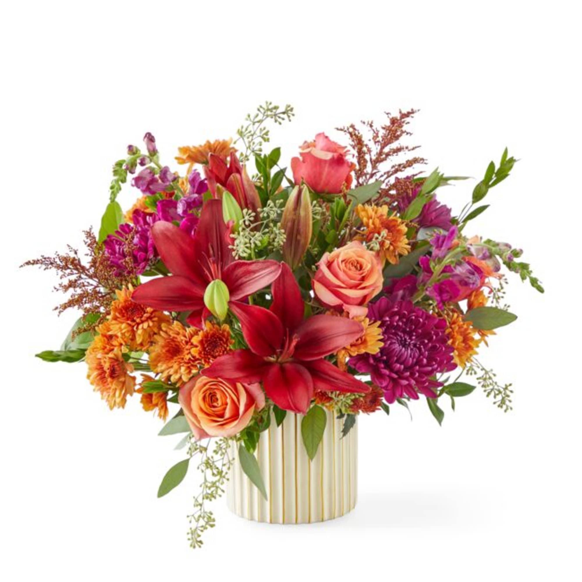 Mixed bouquet of red lilies, peach roses, and purple flowers in a striped vase