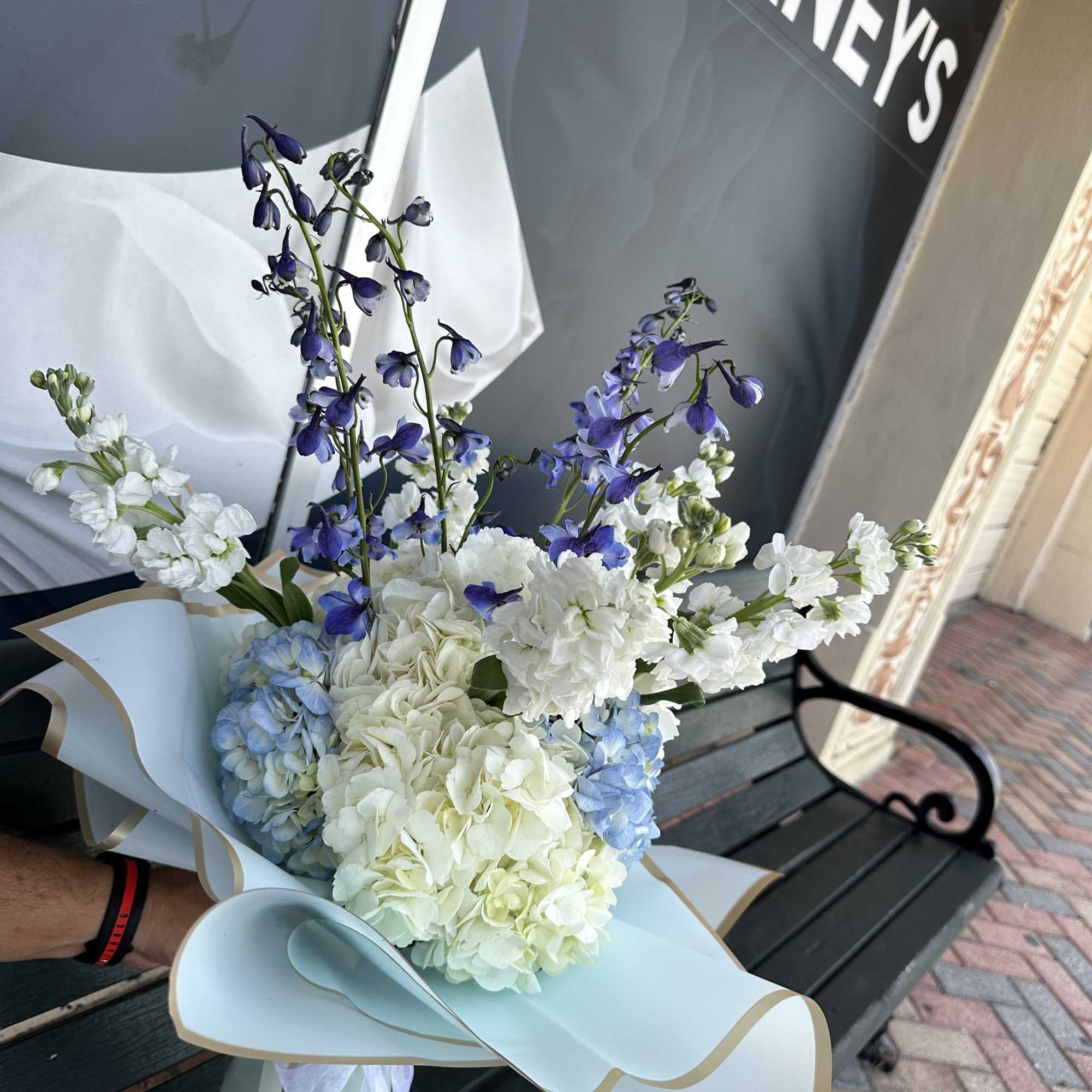 Bouquet of white and blue flowers wrapped in pale paper