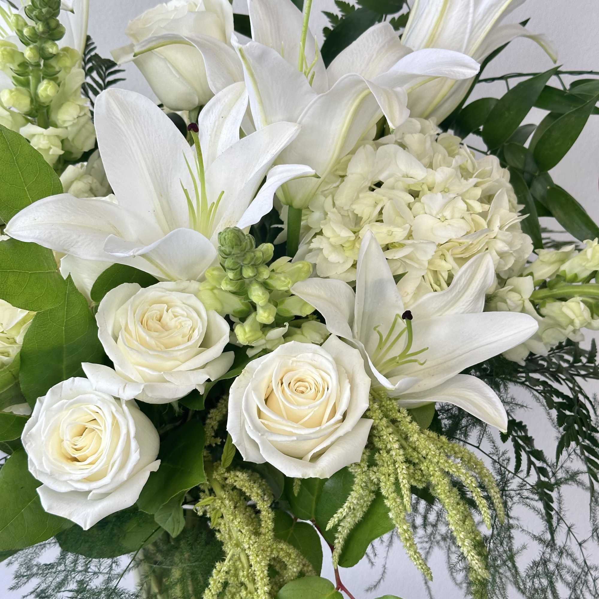 White lilies and roses arranged with pale green accents
