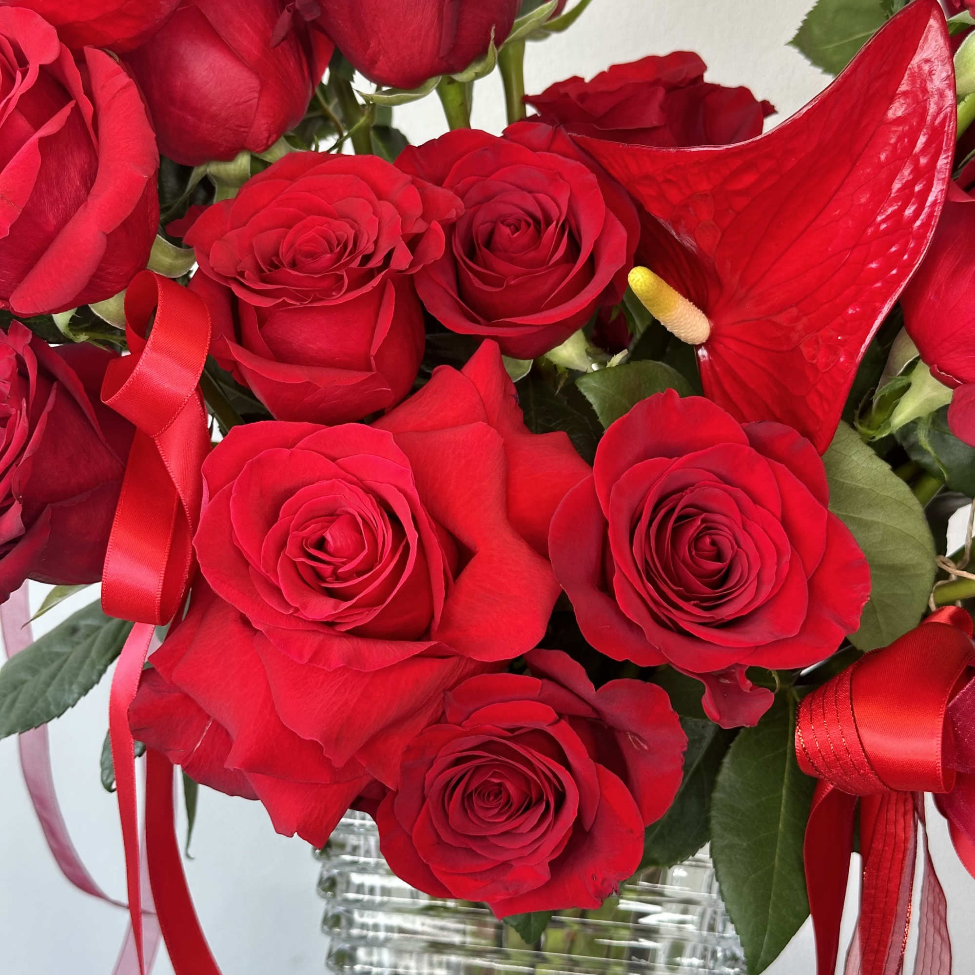 Bouquet of red roses with red ribbon in a glass vase