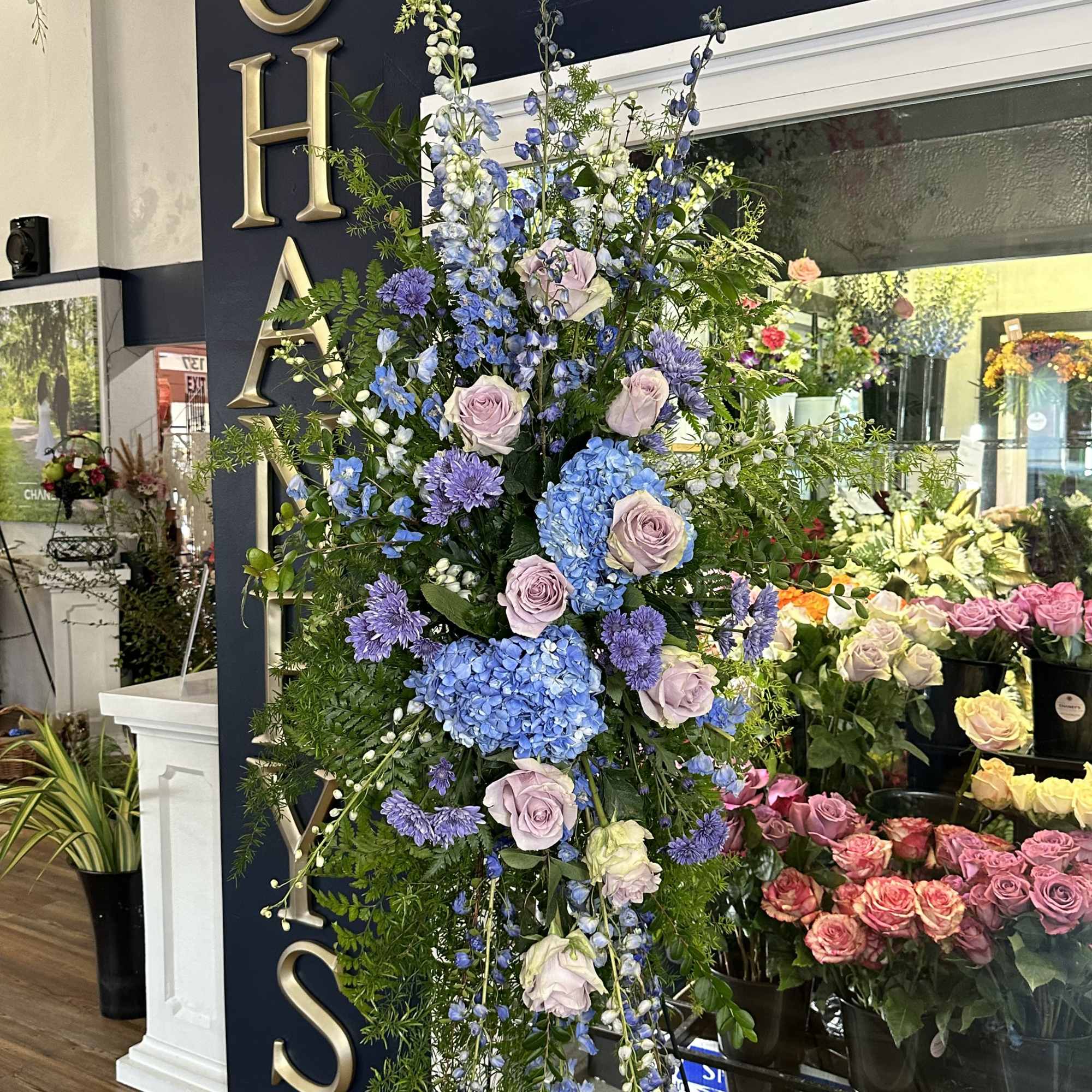 Tall floral standing spray with blue, lavender, and white blooms