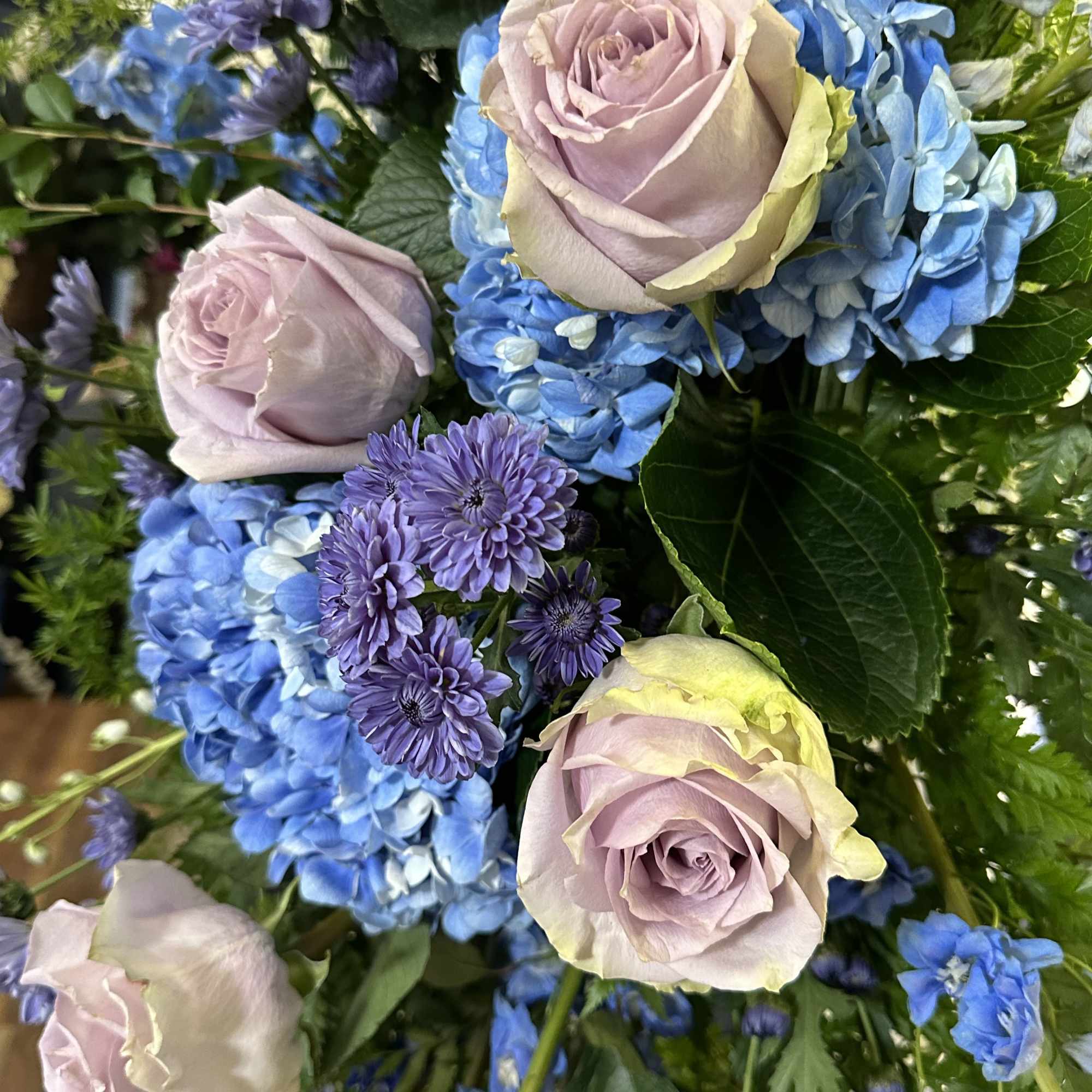 Bouquet of lavender roses with blue hydrangeas and purple daisies