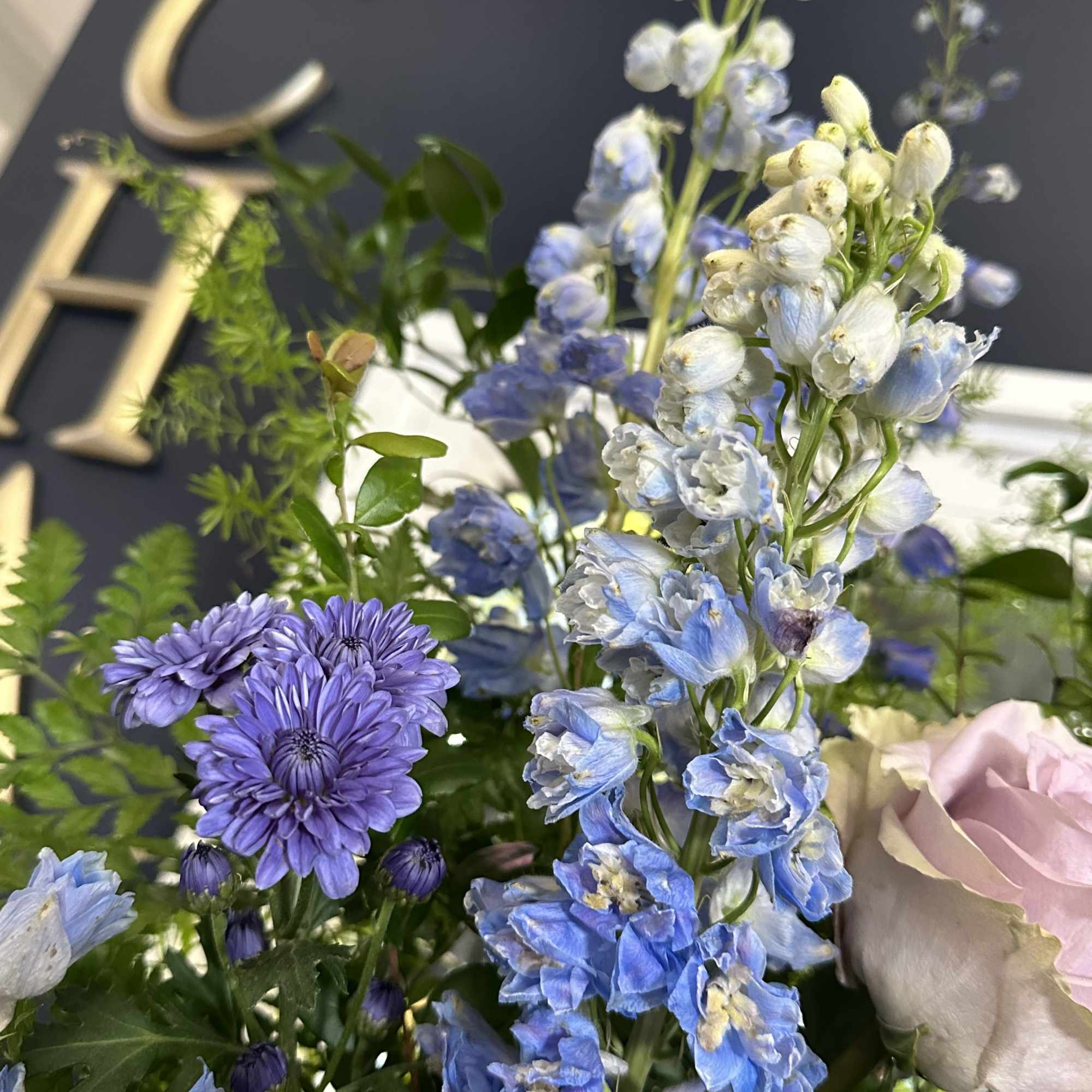 Blue and white floral arrangement with purple blooms and a pink rose