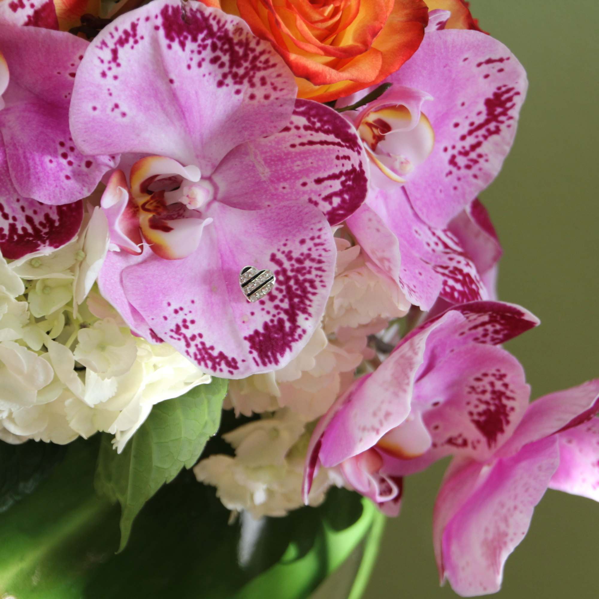 Pink orchids and white hydrangeas with an orange rose