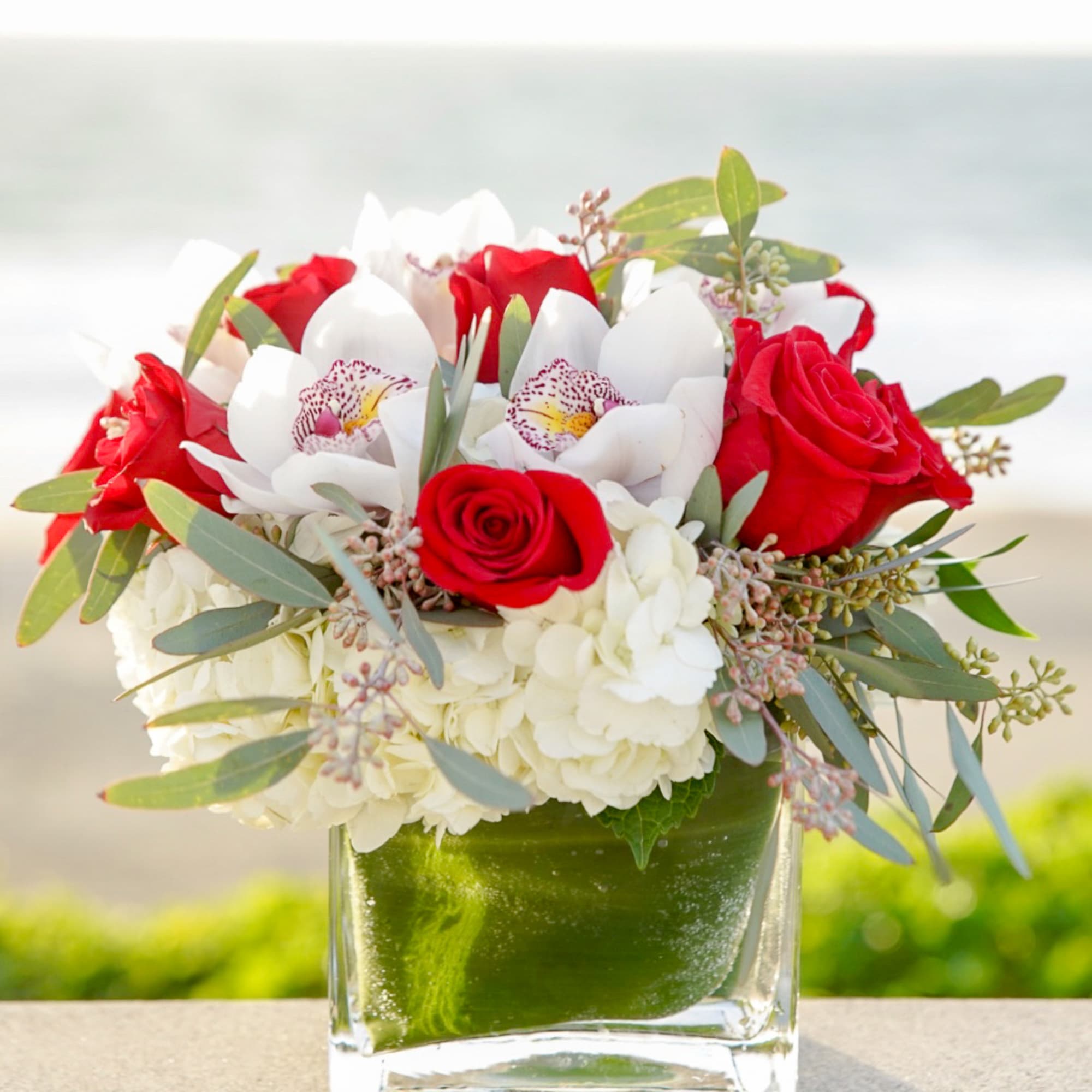 Red roses and white orchids in a square glass vase