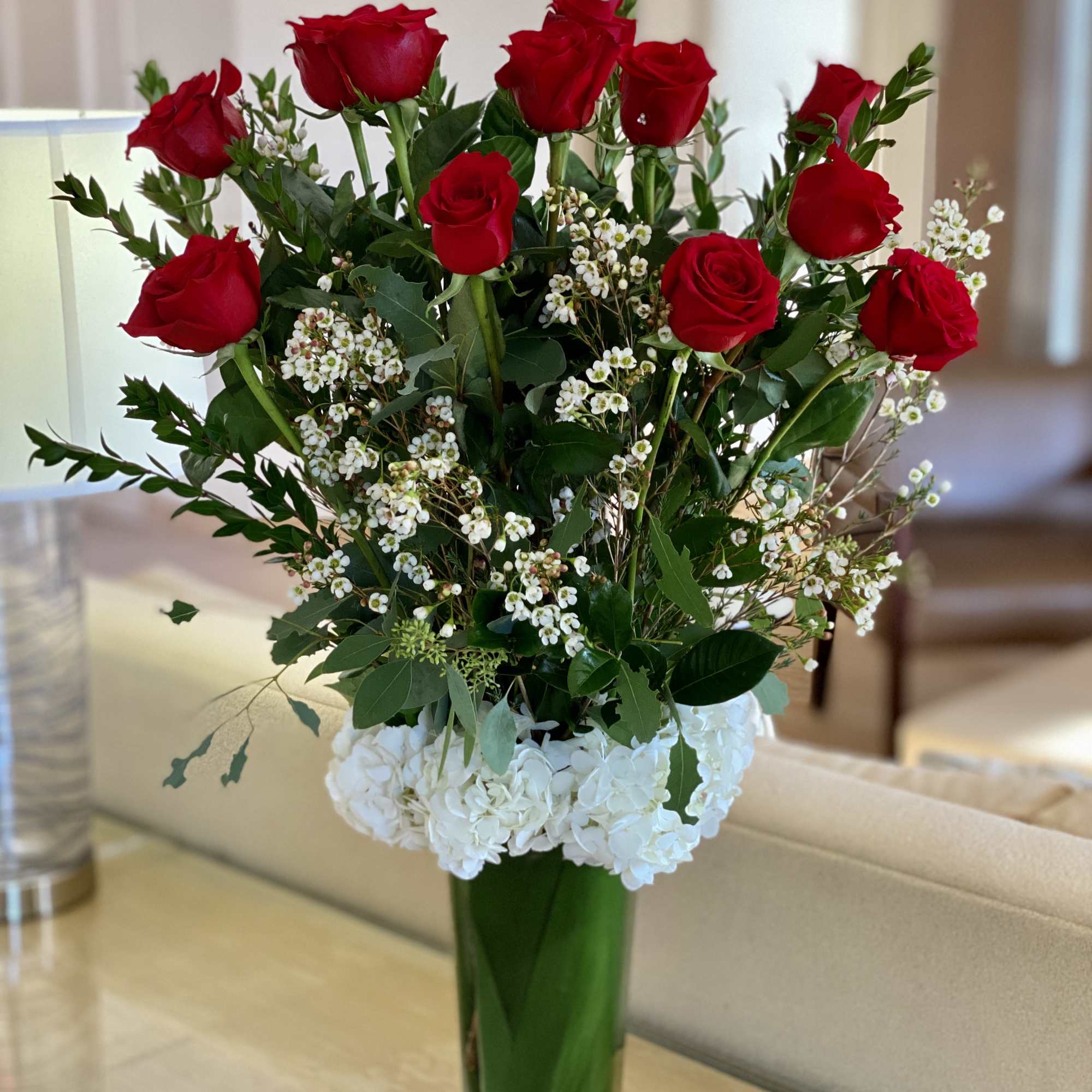 Red roses and white hydrangeas in a tall glass vase