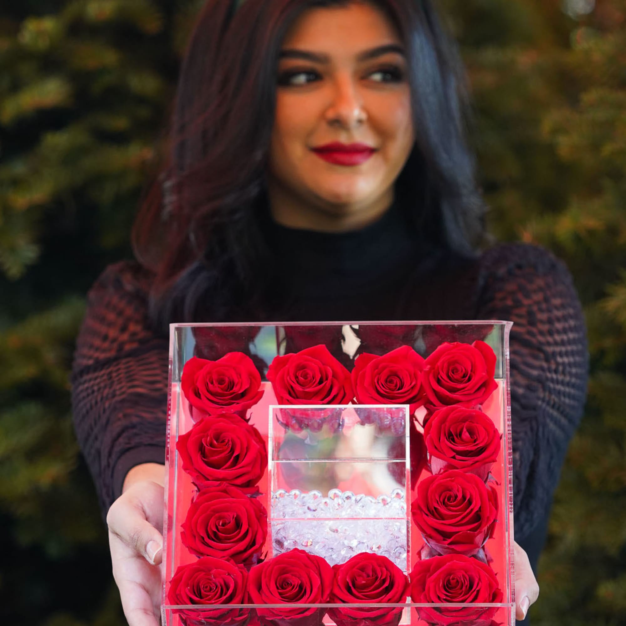 Woman holding a clear box filled with red roses